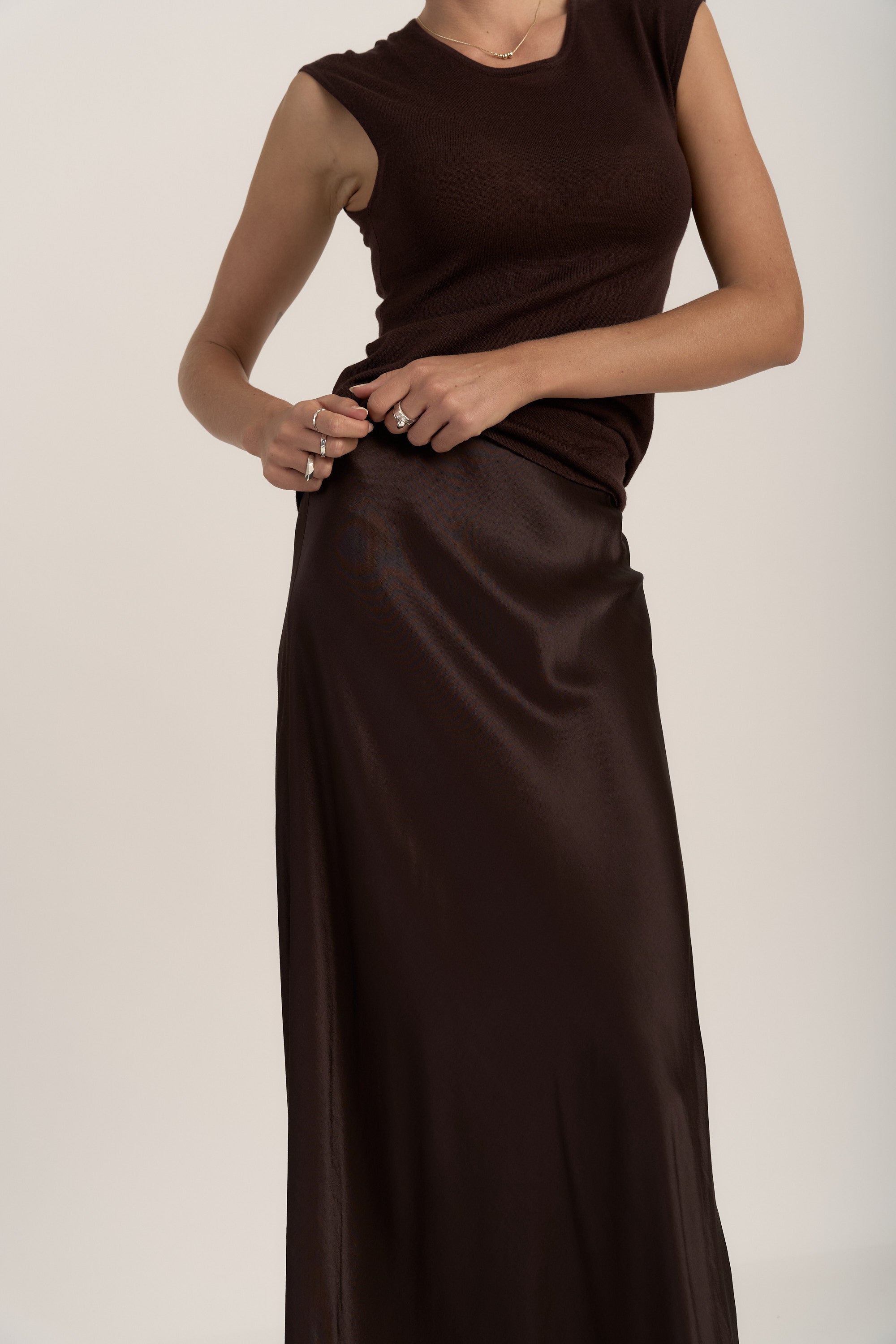 Woman in Max's The Slip Skirt and a sleeveless brown top, posing against a plain background.