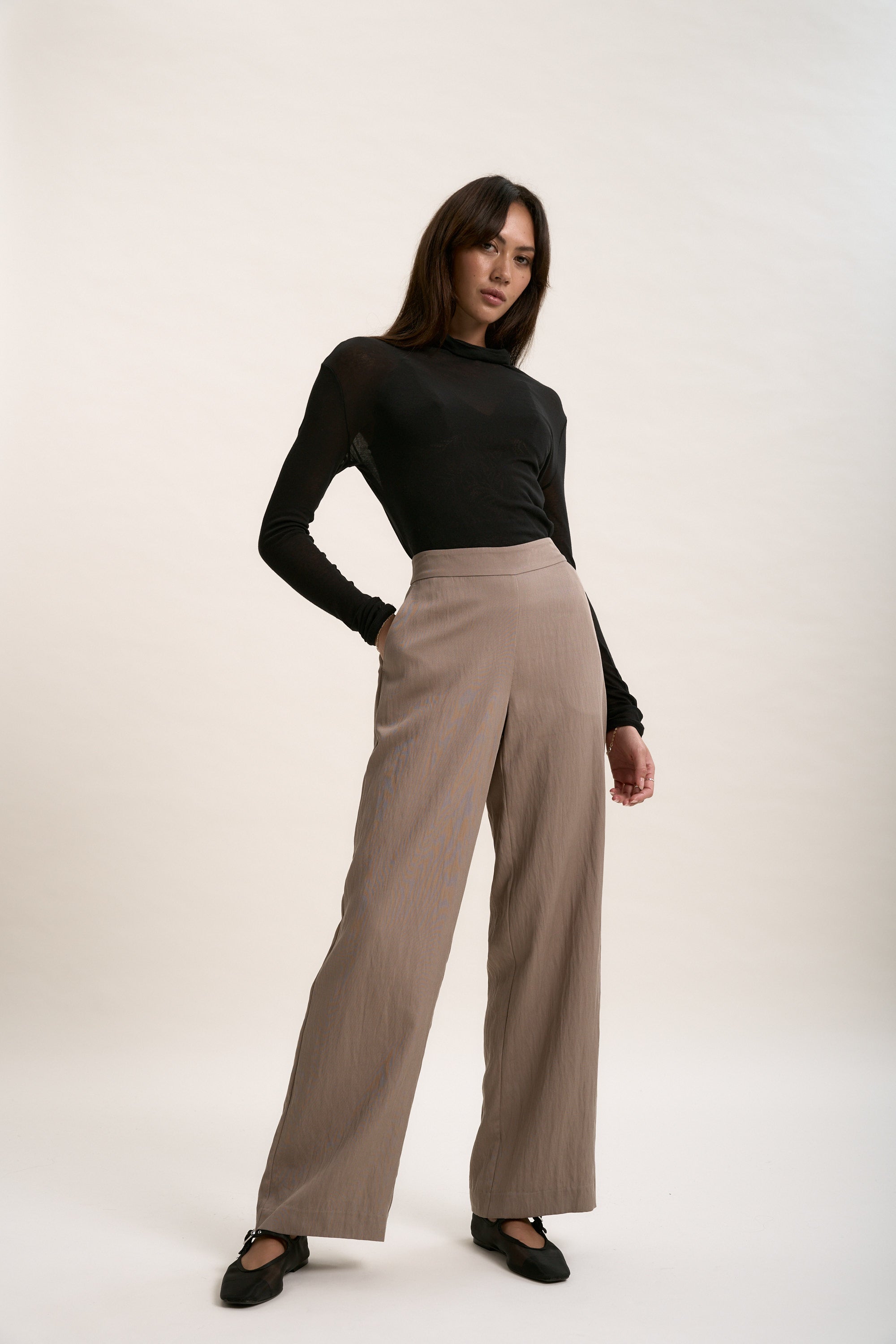 Woman in black top and Max’s The Ultimate Wide Leg Pants poses against a plain background.