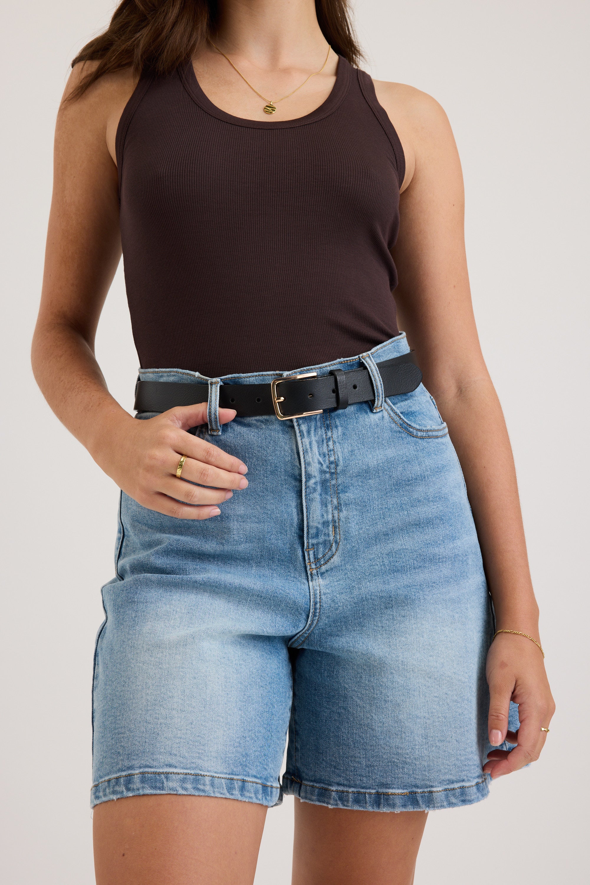 Woman in Max's Ultimate Denim Short, sleeveless brown top, black belt, and minimal jewelry.