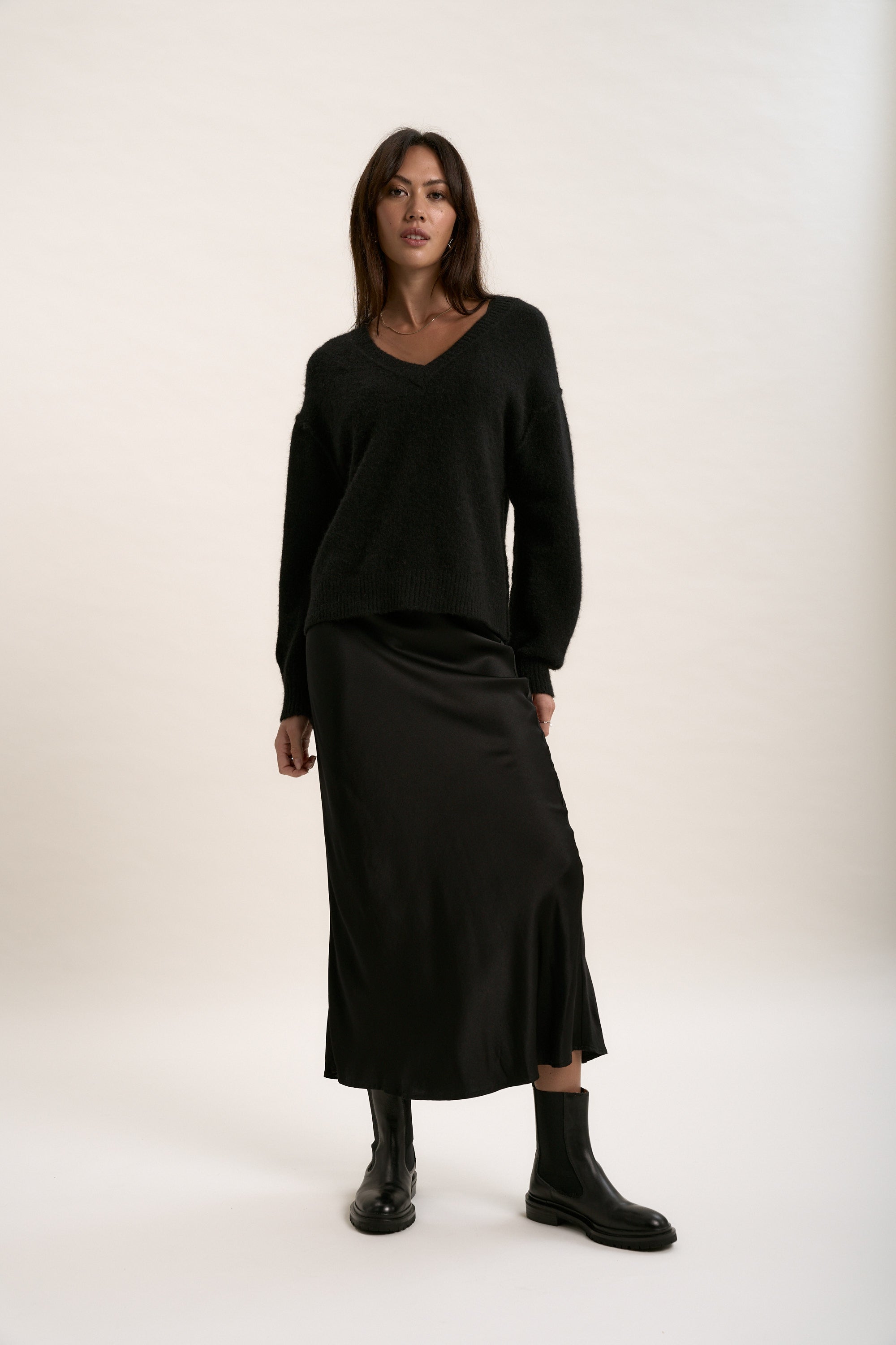 Max's Luxe Whisper V Neck Sweater styled with a black skirt, featuring sustainable knitwear.