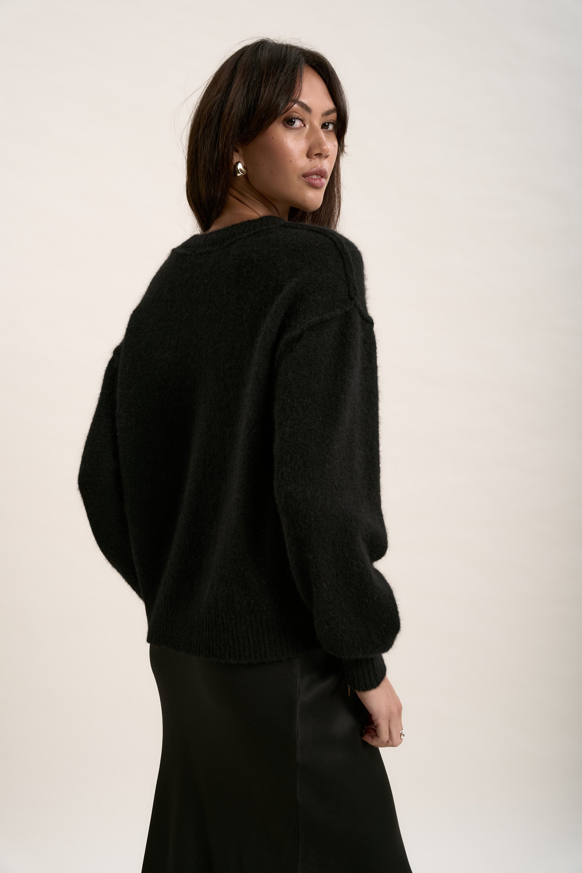 Woman in The Luxe Whisper V Neck Sweater by Max looks over her shoulder against a light background.