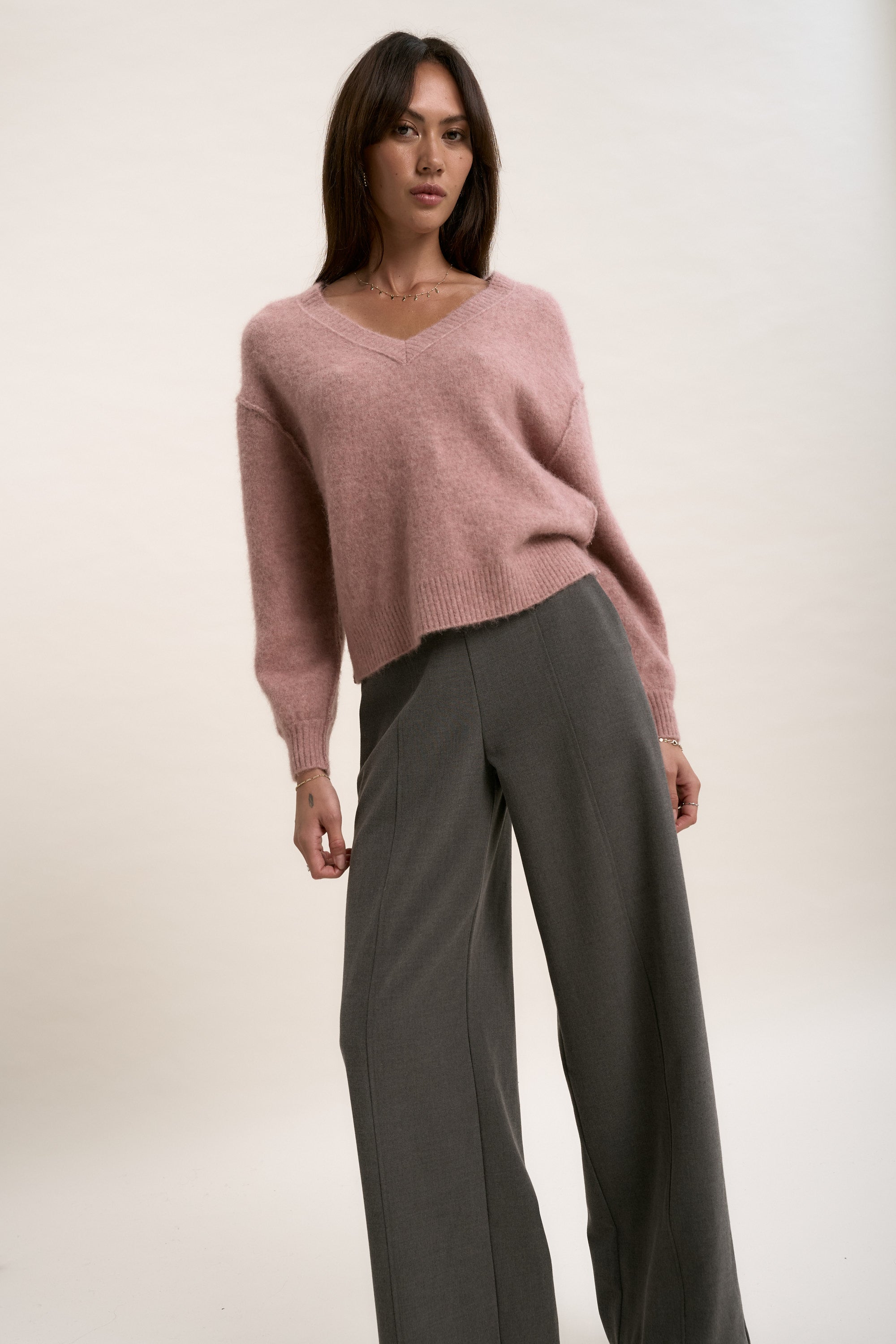 Max’s Luxe Whisper V Neck Sweater paired with gray wide-leg pants against a plain backdrop.