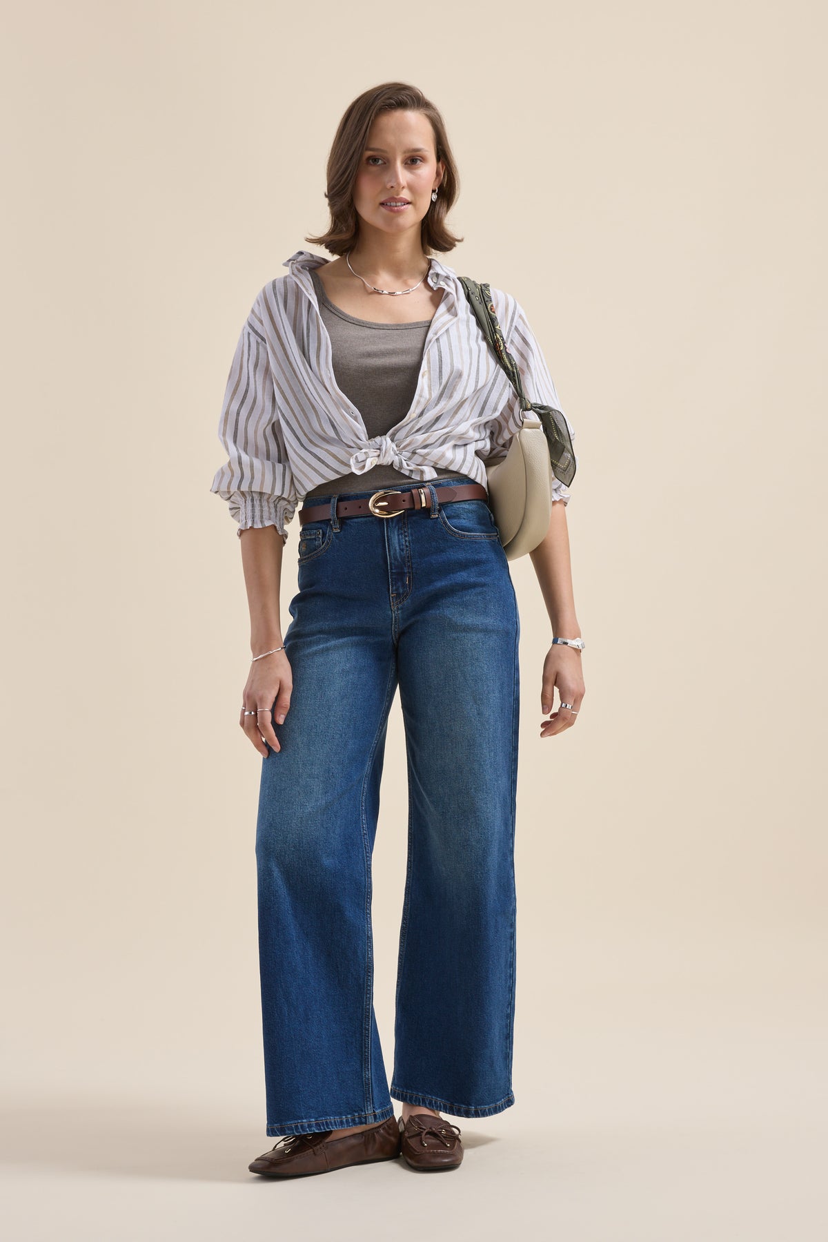 Woman in striped shirt, Elementary Basics Rib Cami by Elementary, wide jeans, loafers, bag stands.
