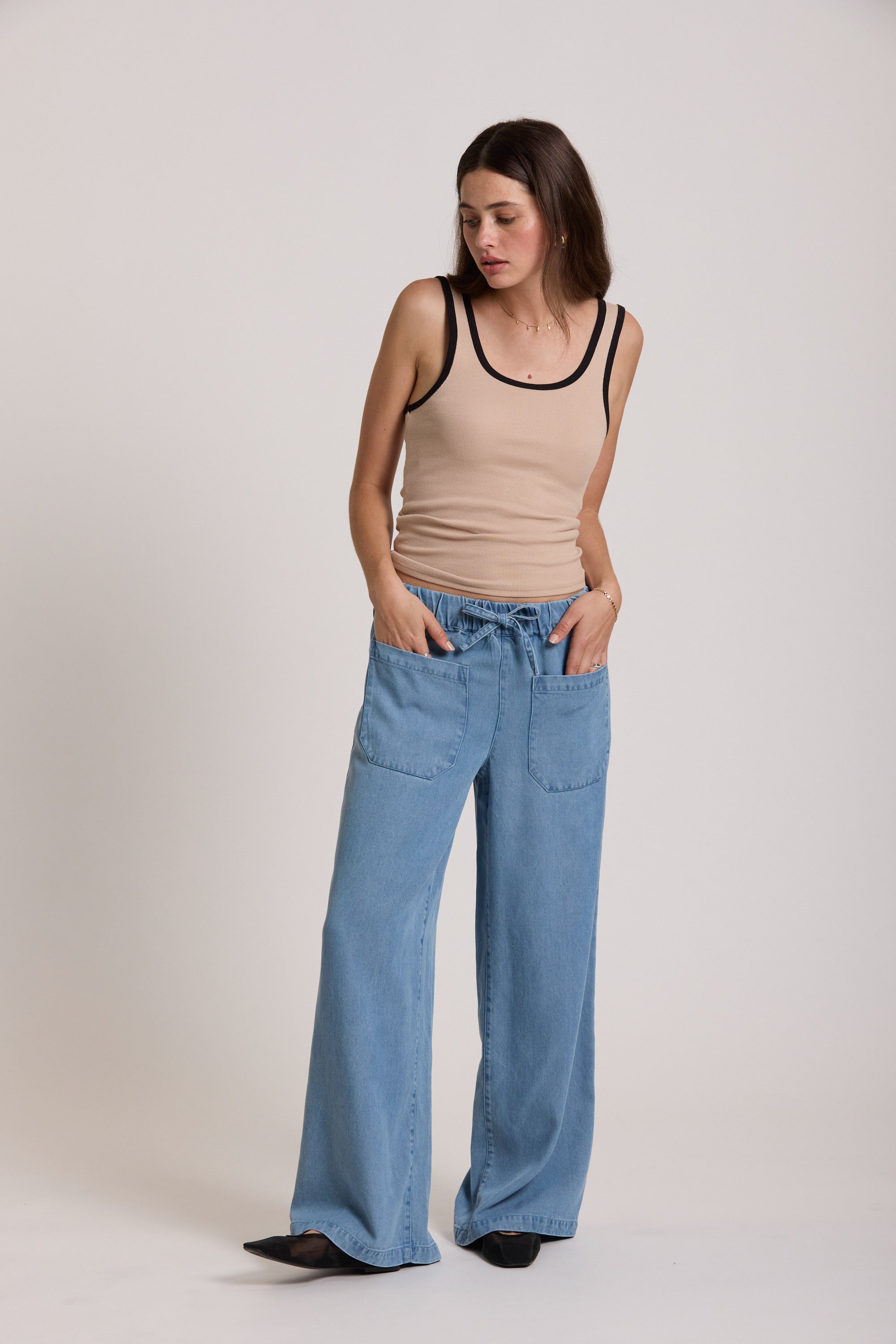 Woman wears The Contrast Trim Tank by Max with wide-leg blue jeans, hands in her pockets.