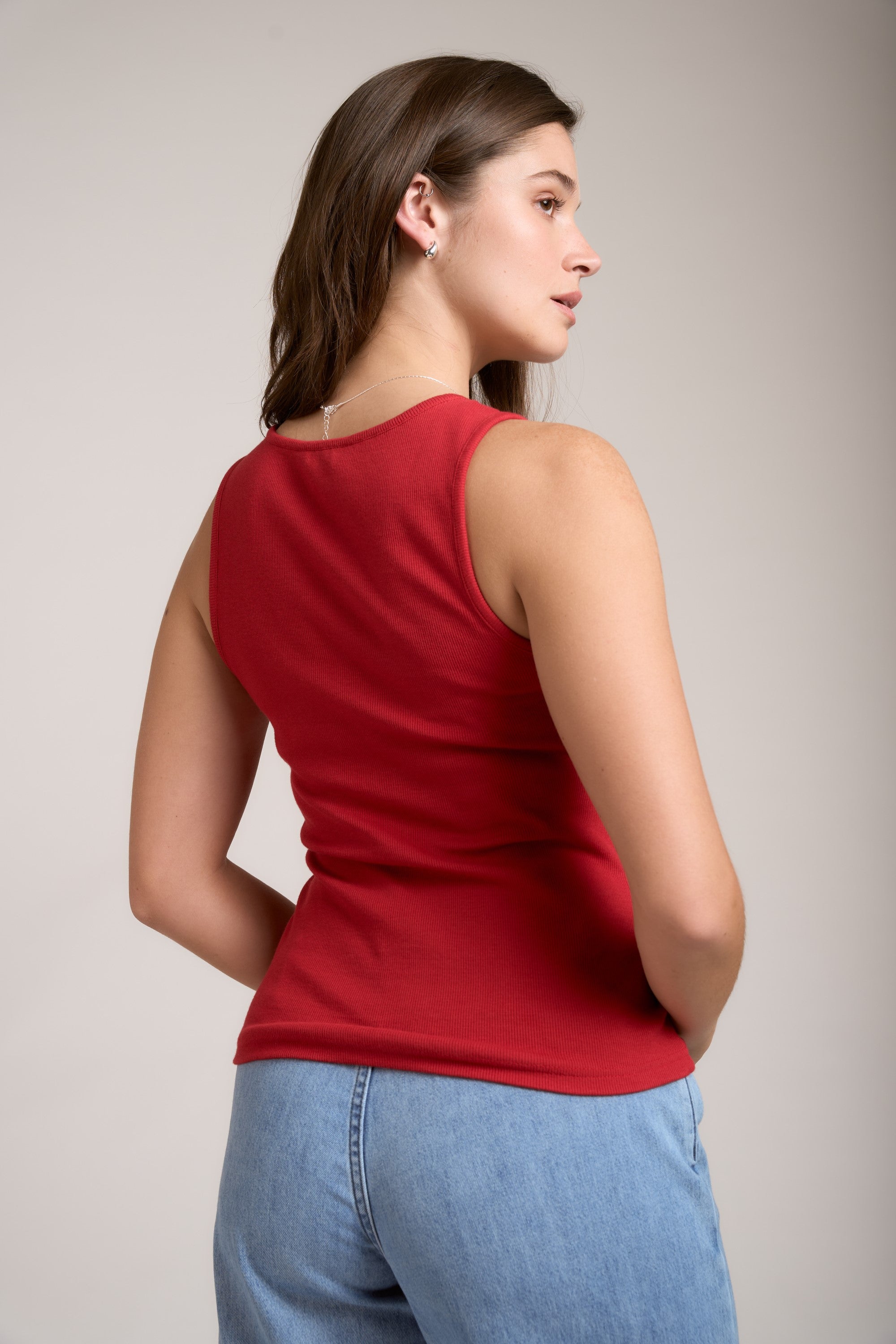 Woman in a Max Eliza Ring Detail Tank and blue jeans stands with her back to the camera.