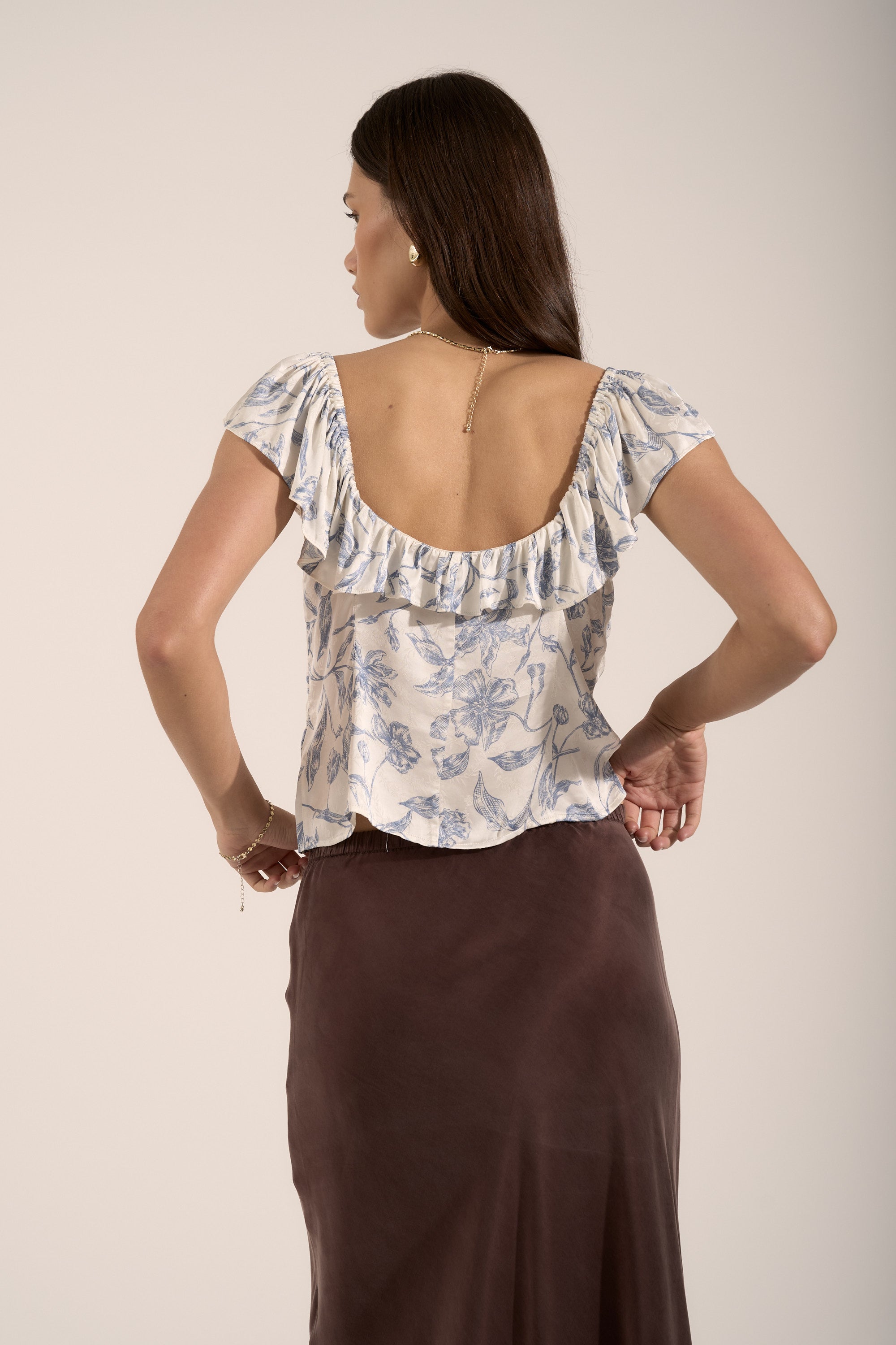 Woman in Max Ingrid Frill Detail Blouse and brown skirt, showing ruffled back detail.