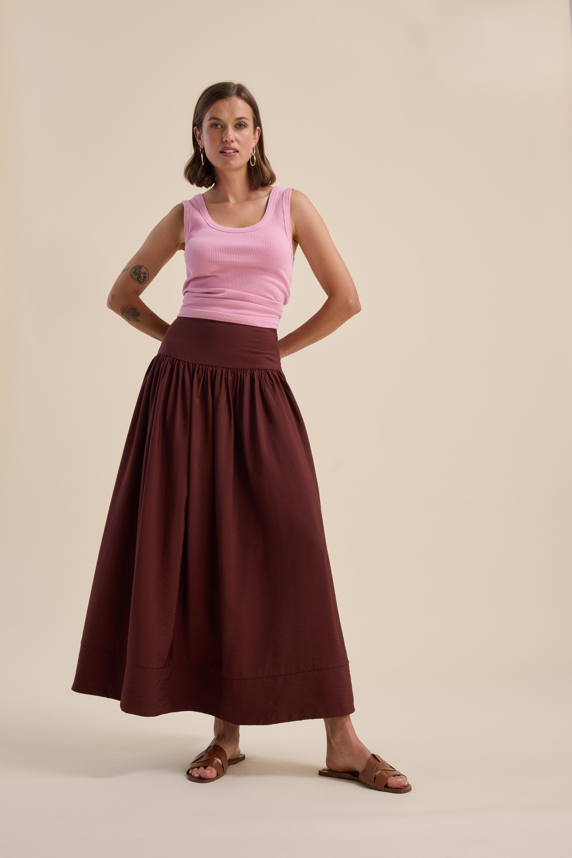 Woman in a pink tank top and Max Carrie Tiered Skirt stands against a beige background.