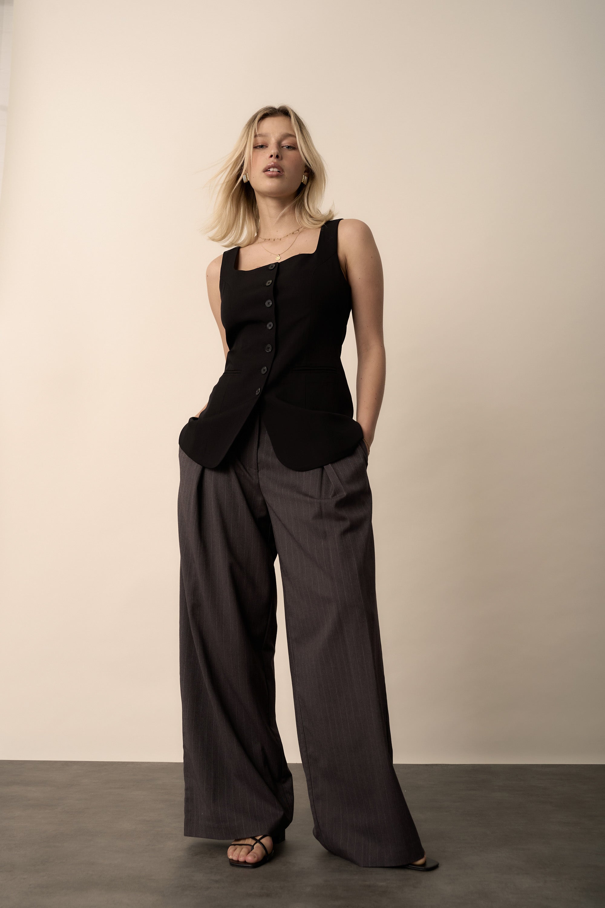 Woman in The Button Front Vest by Max and wide-leg gray pants stands against a plain background.