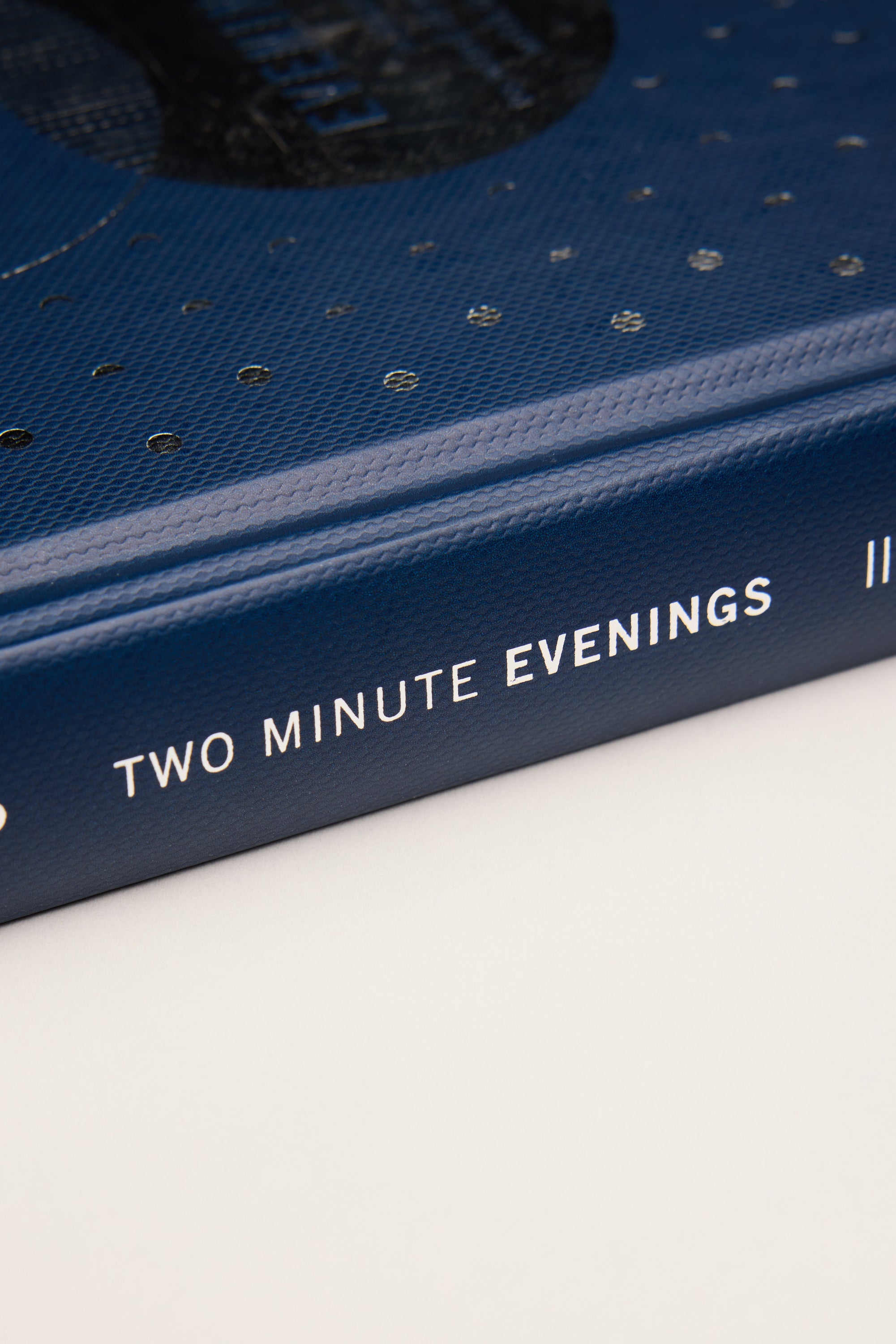 Close-up of a blue hardcover Two Minute Evenings Book by Other, featuring white spine text; ideal for stress relief and improving sleep habits.