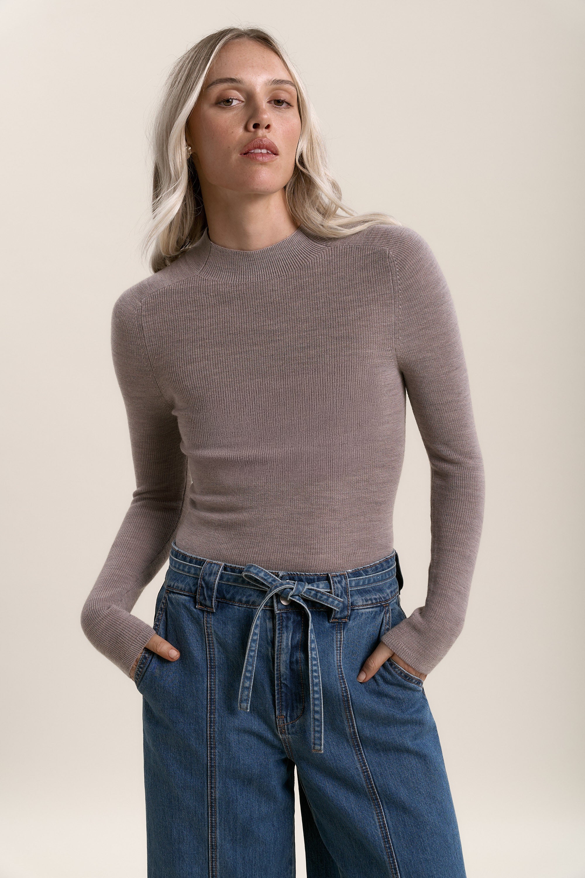 Woman in Max Alexis Merino Long Sleeve, ribbed taupe top, and wide-leg blue jeans with tied waist.