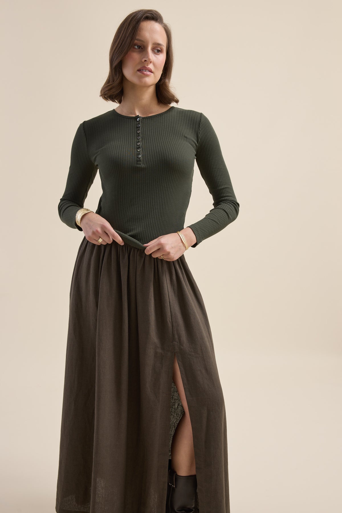 Woman in the Elementary Ribbed Henley and a brown front-slit skirt, posing indoors.
