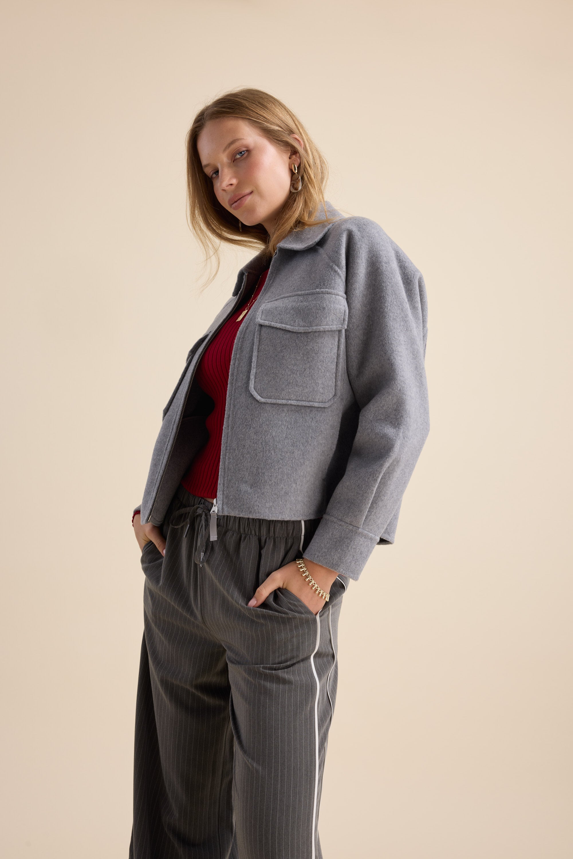 Woman in The Zip Front Wool Blend Cropped Coat by Max poses against a beige backdrop.