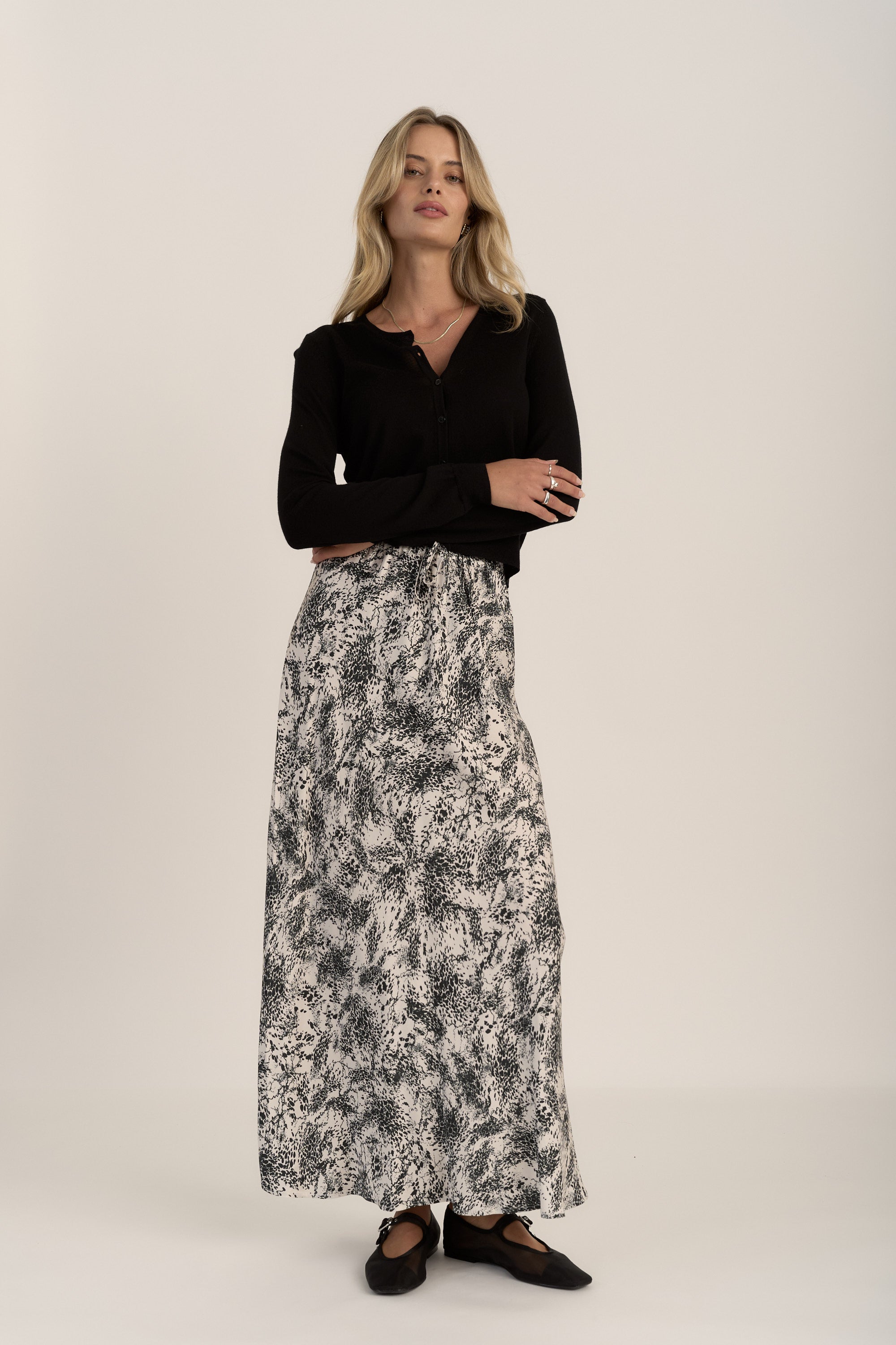 Woman in Max Henry Maxi Slip Skirt and black top, arms crossed against a plain background.