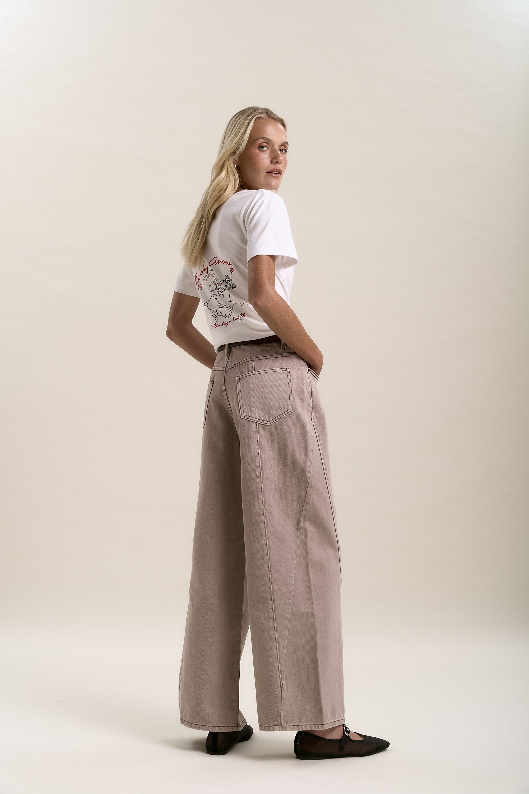 Woman in a white tee and Max Lisbon Panel Detail Jeans, standing and looking over her shoulder.