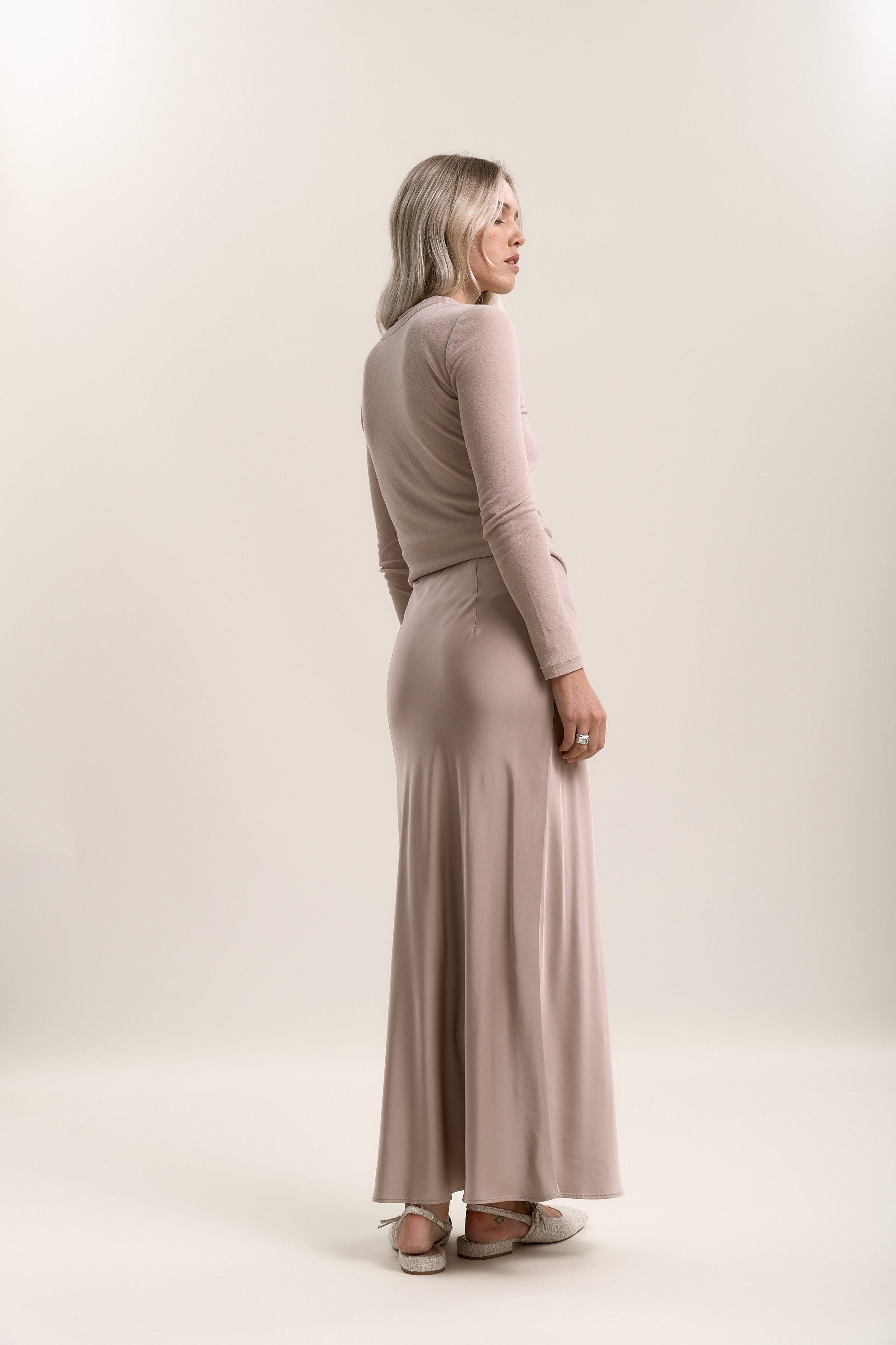 Woman in a light pink long-sleeve top and Max Holly Slip Skirt on a neutral background.