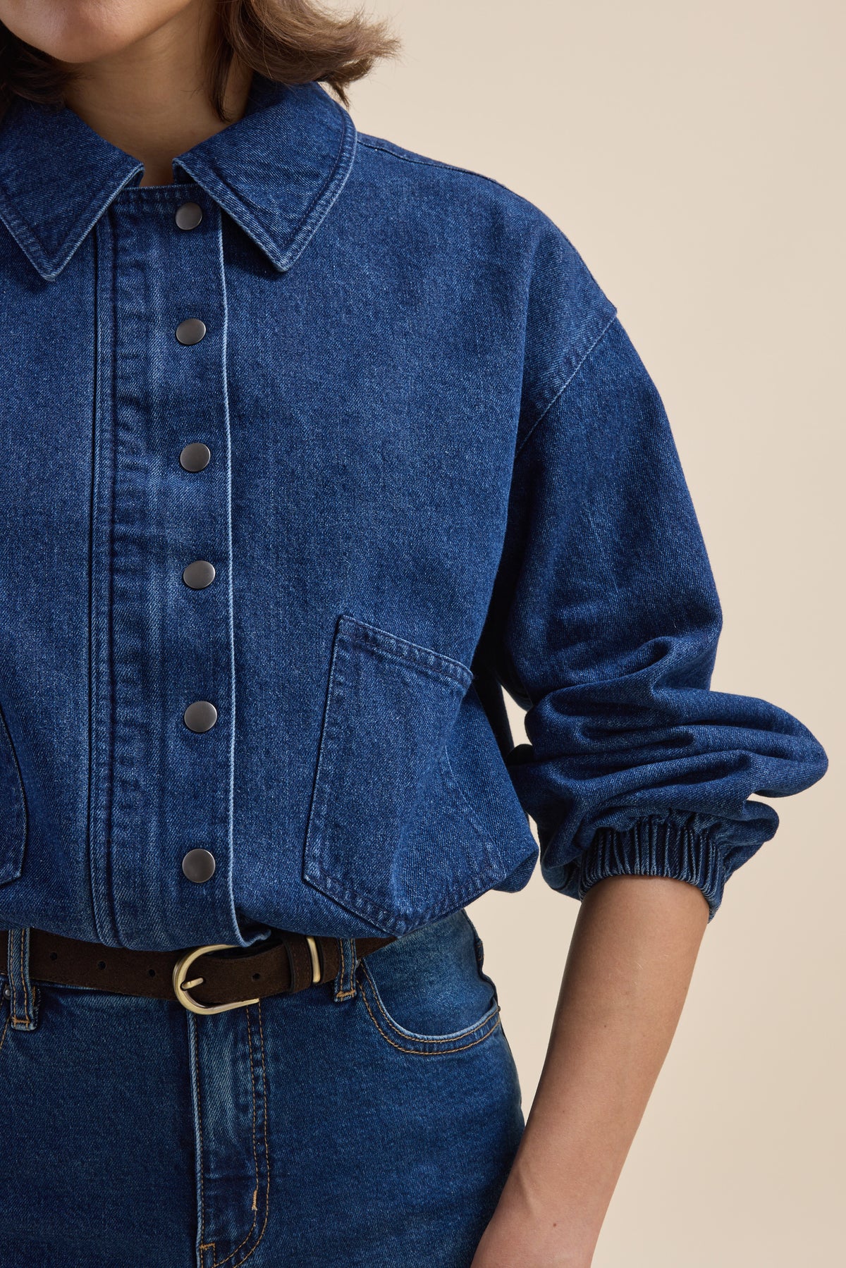 Person wears Elementary Relaxed Jacket in organic cotton denim with jeans, black belt, arm bent.