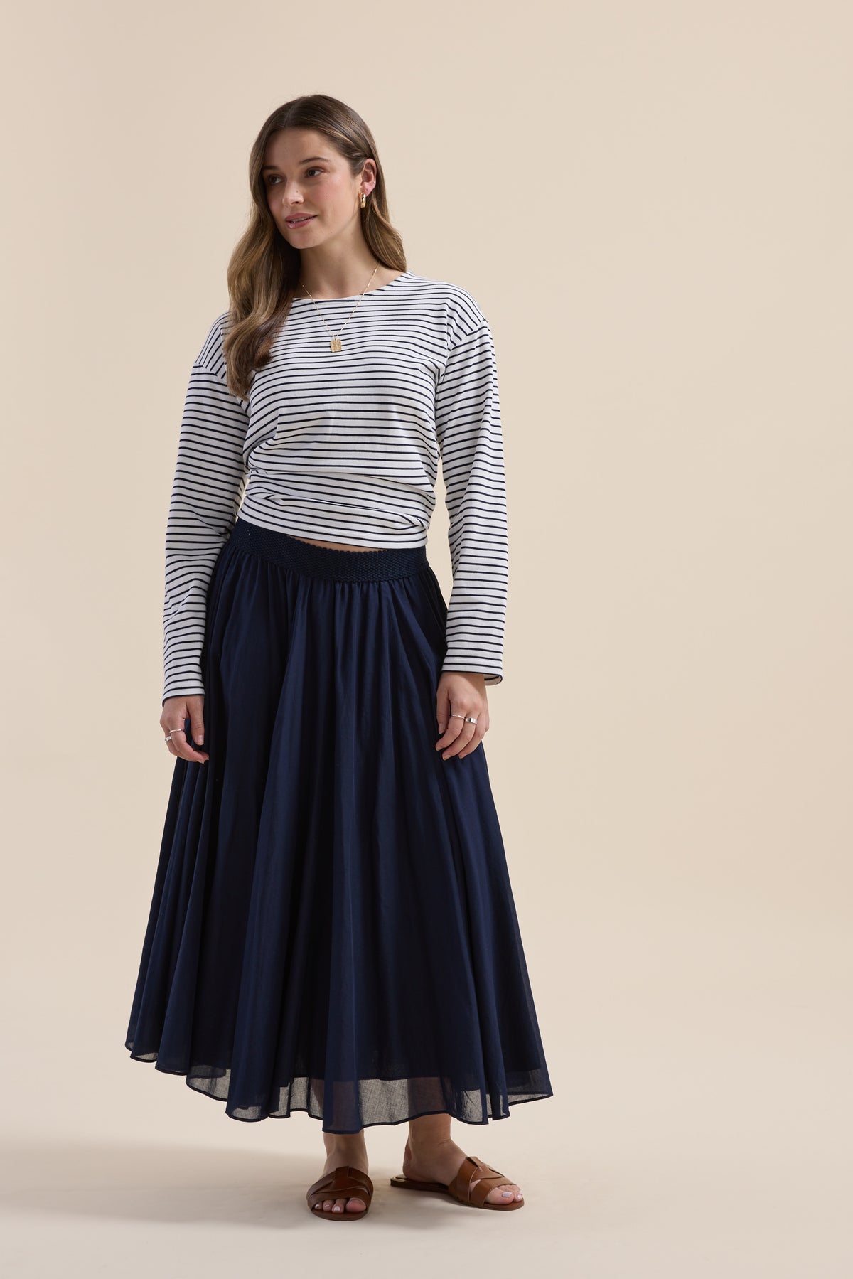 Woman wearing striped long-sleeve top, Elementary Gathered Skirt, and sandals, facing forward.