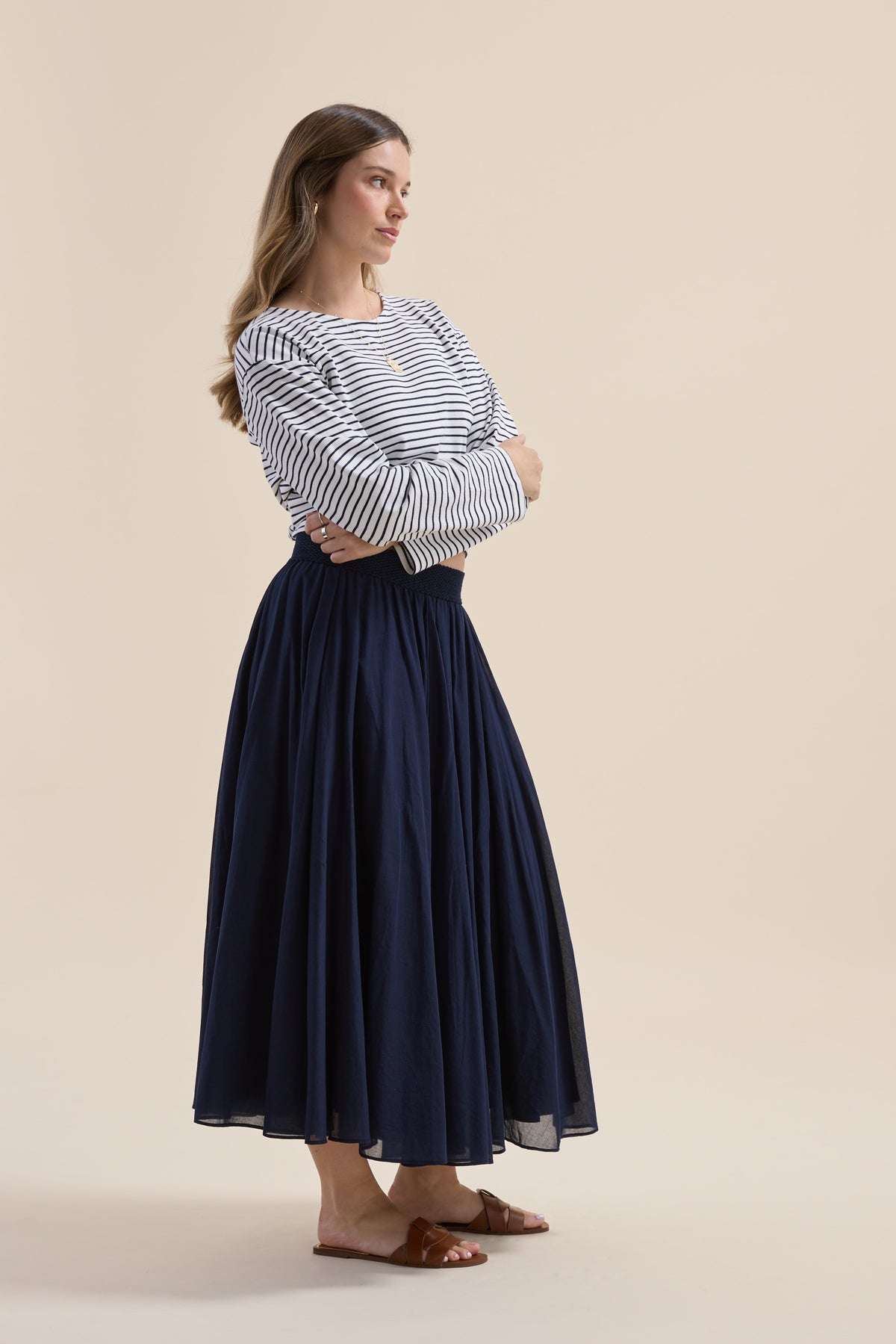 Woman in long-sleeve top and Elementary Gathered Skirt stands with arms crossed, side view.