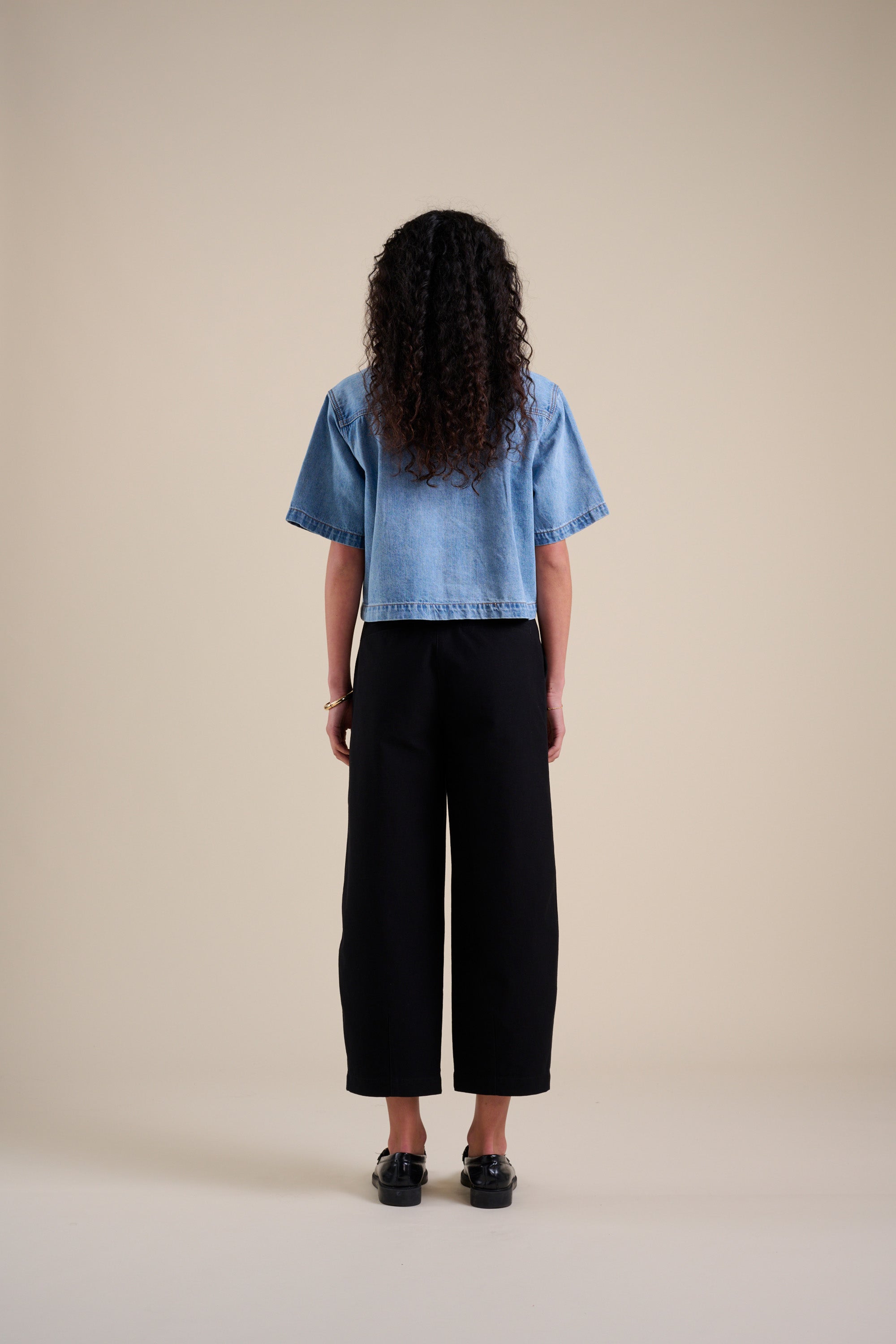 Person faces away in a denim shirt and Max Eden Barrel Leg Pants in high-rise black.