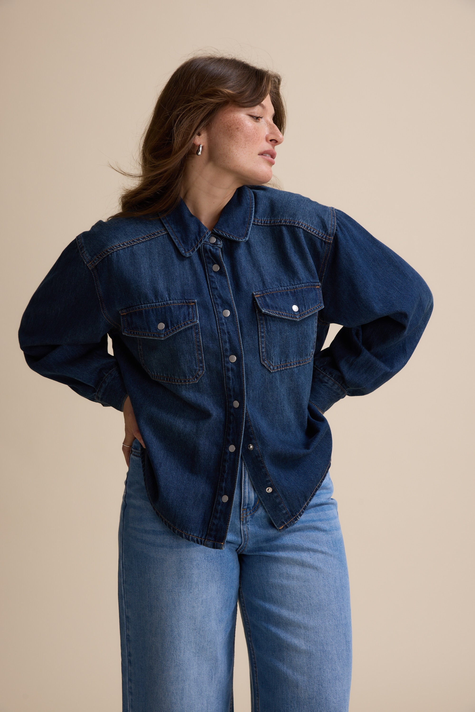 Woman in Max's Sabrina Cropped Denim Jacket, looking sideways with hands behind her back.