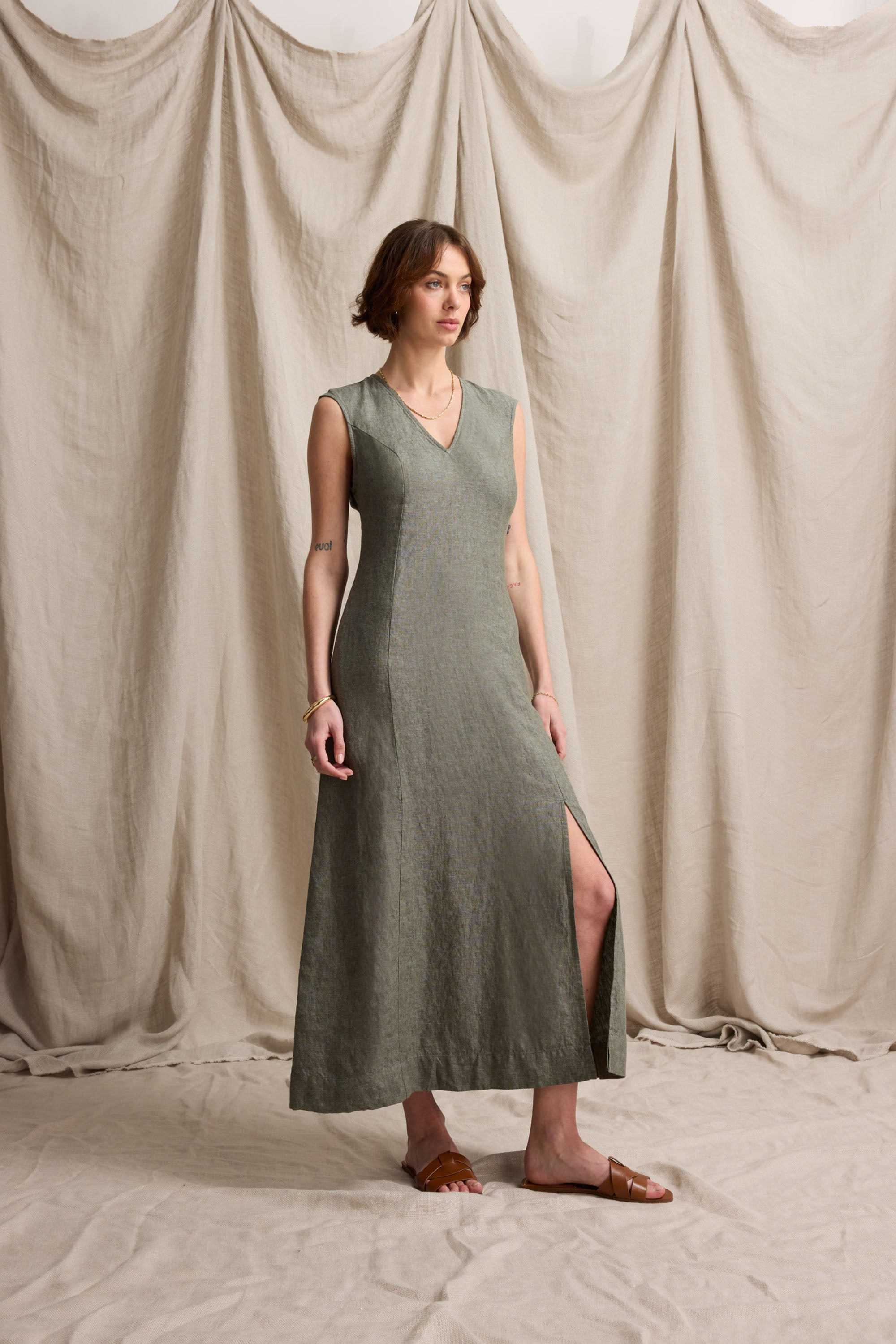 Woman in the Max Alice V Neck Linen Dress stands on fabric with a draped backdrop.