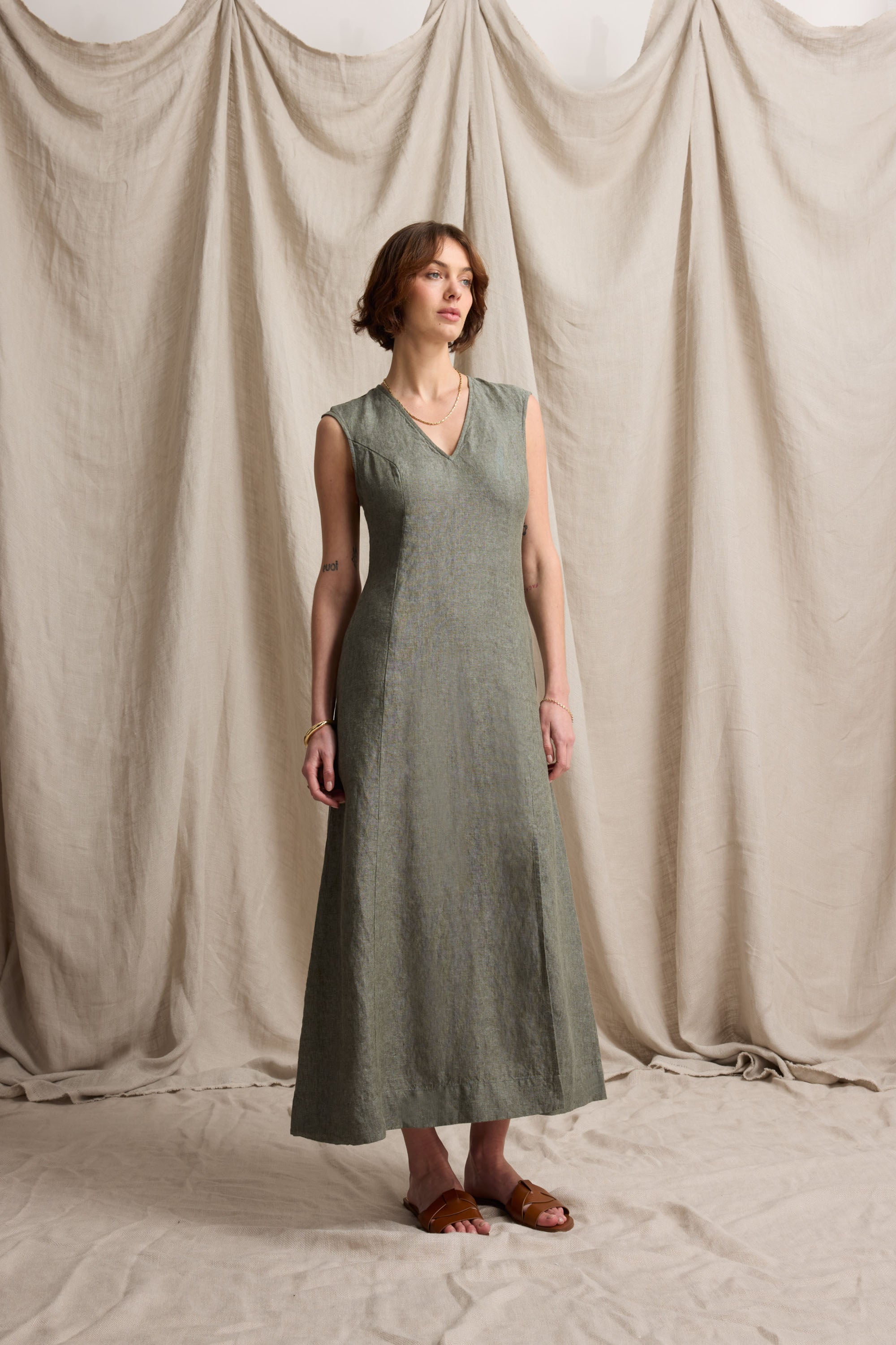 Woman in the Max Alice V Neck Linen Dress and sandals before draped beige fabric backdrop.