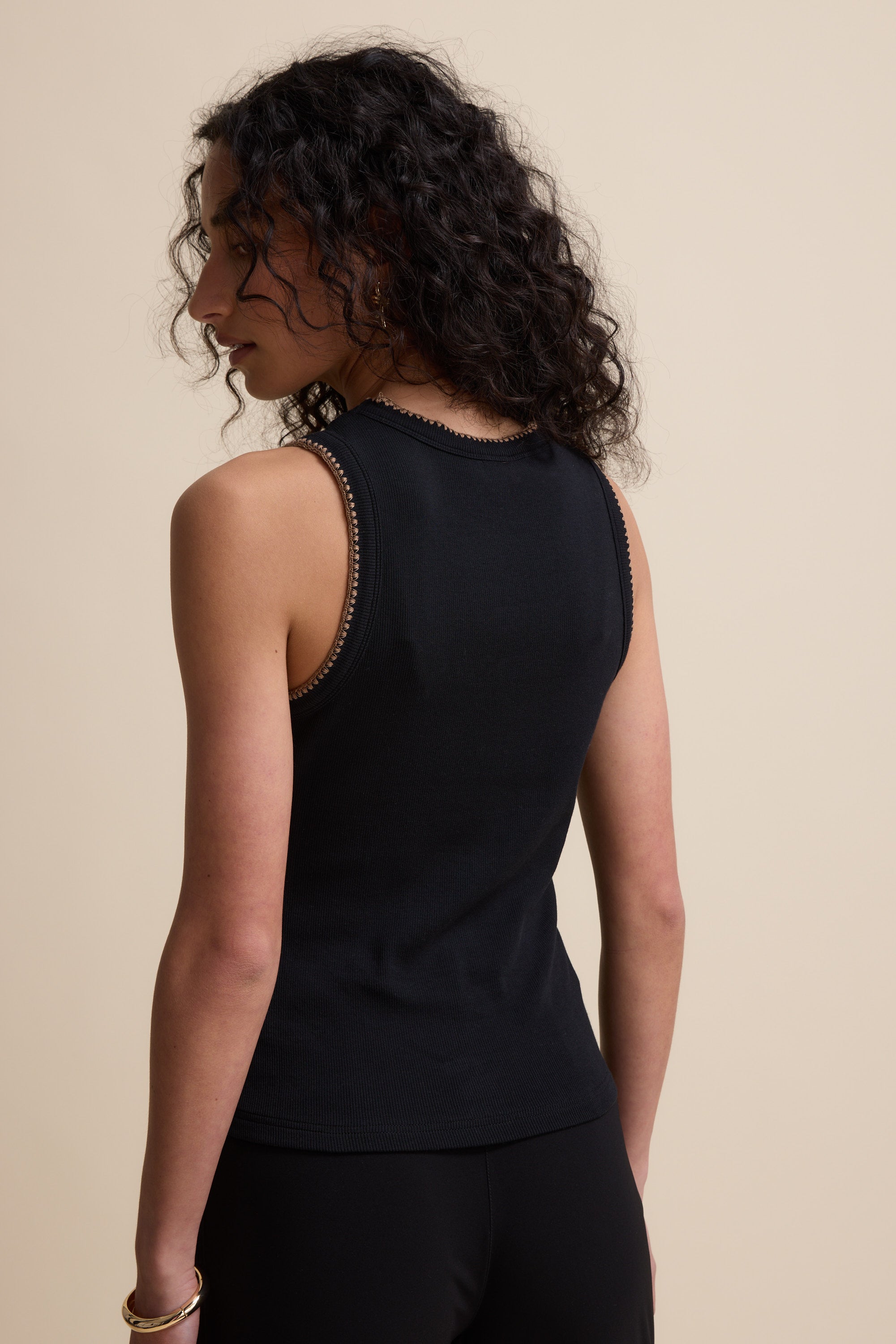 A woman with curly hair wears the Max Stitch Detail Tank, facing away from the camera.
