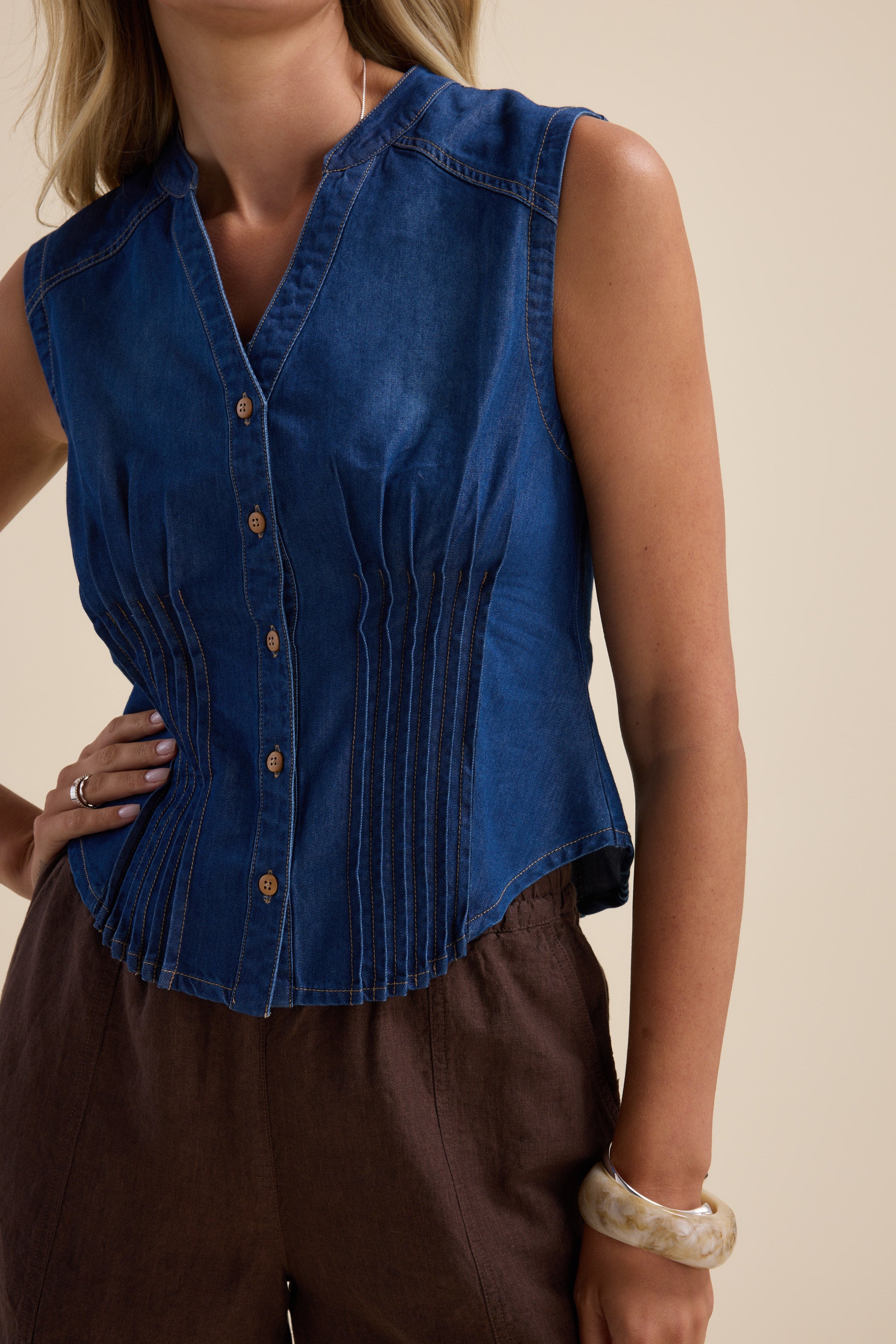 Woman in a Max Brooklyn Tuck Detail Denim Shirt, brown pants, and a bangle bracelet.
