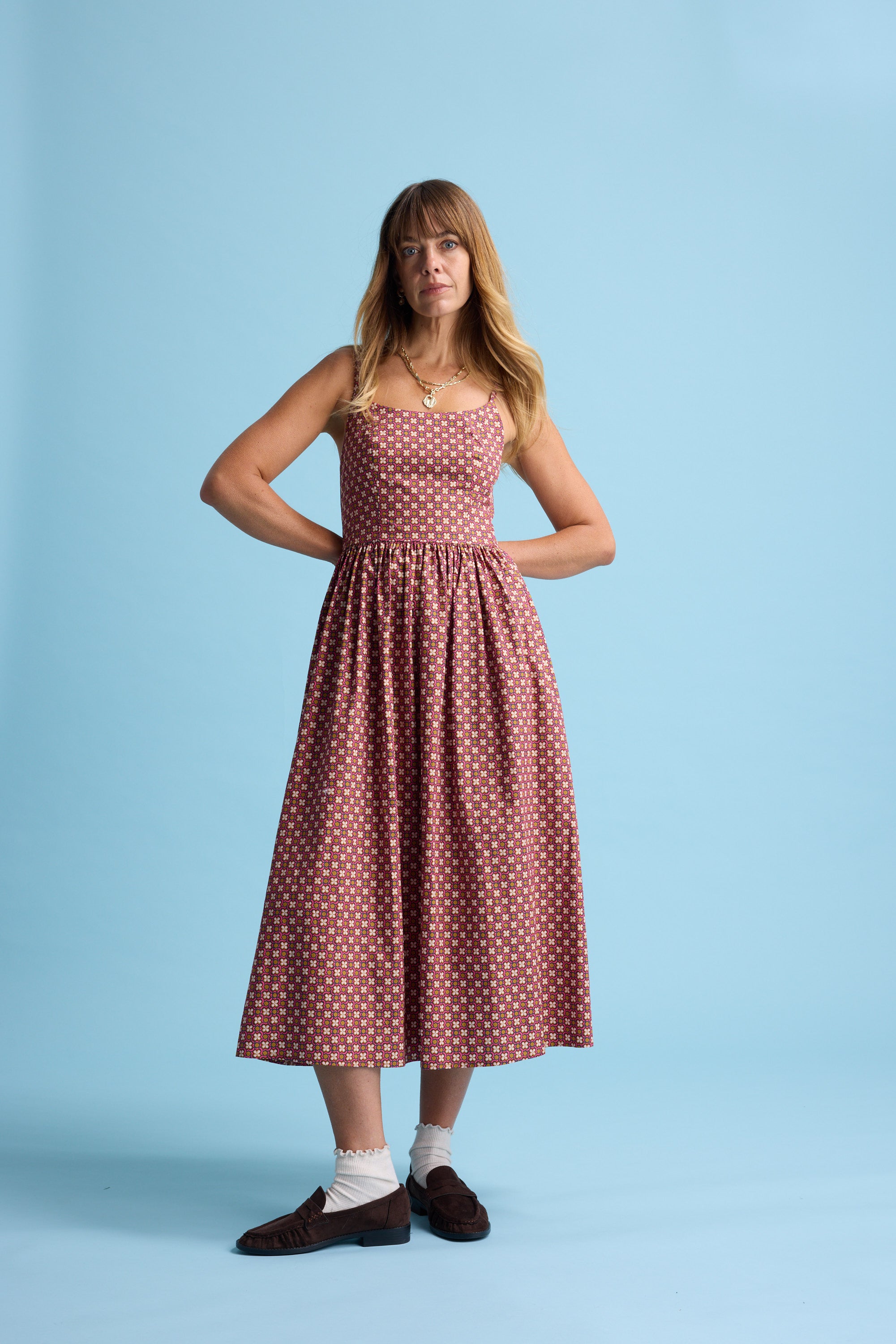 Woman in the Max Eliza Midi Dress stands confidently against a blue background.