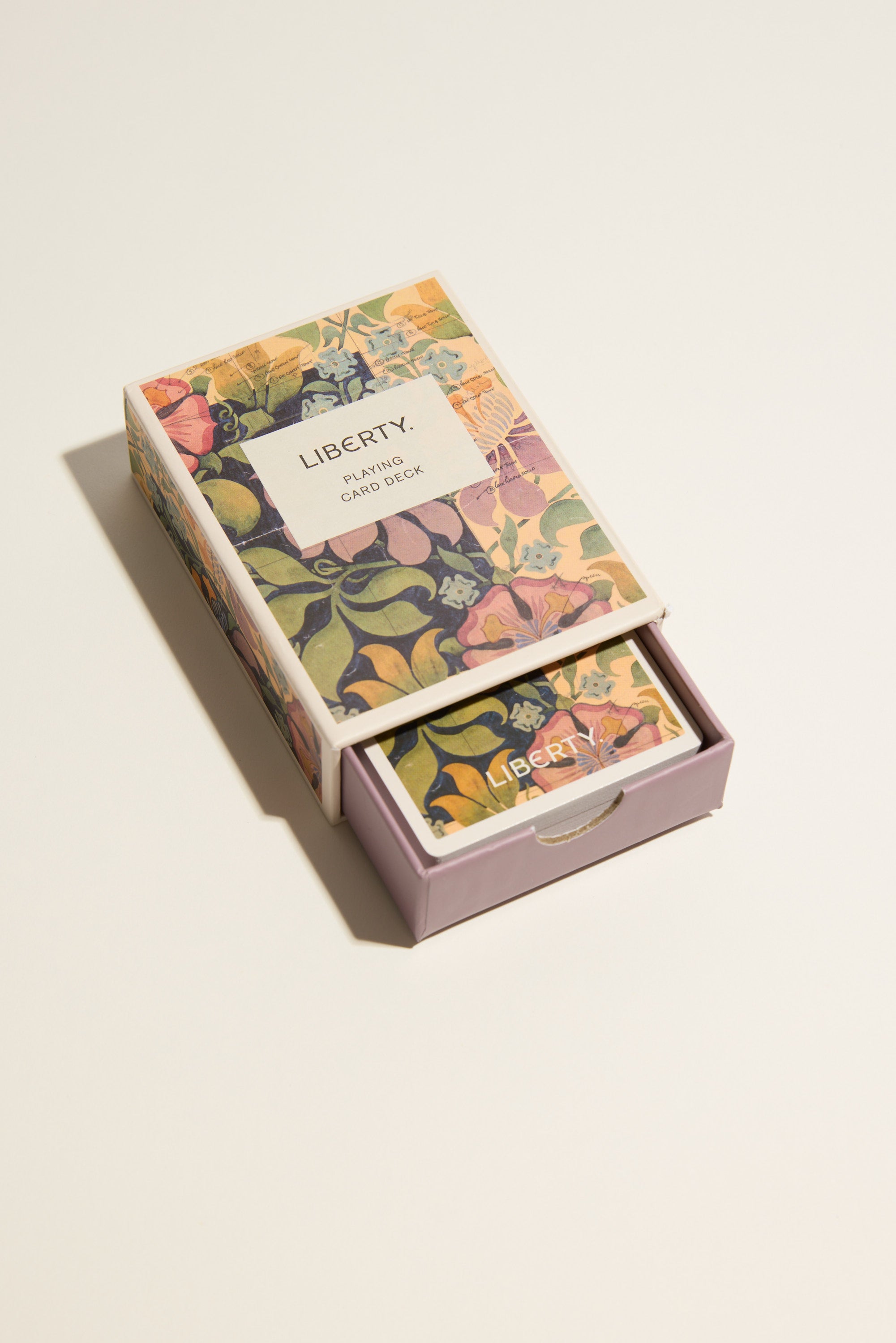 The Liberty Archive Playing Card Deck by Other features a floral-patterned box with a matching draw-style tray, partially open to reveal luxury cards inside, elegantly displayed on a light surface with classic British design.
