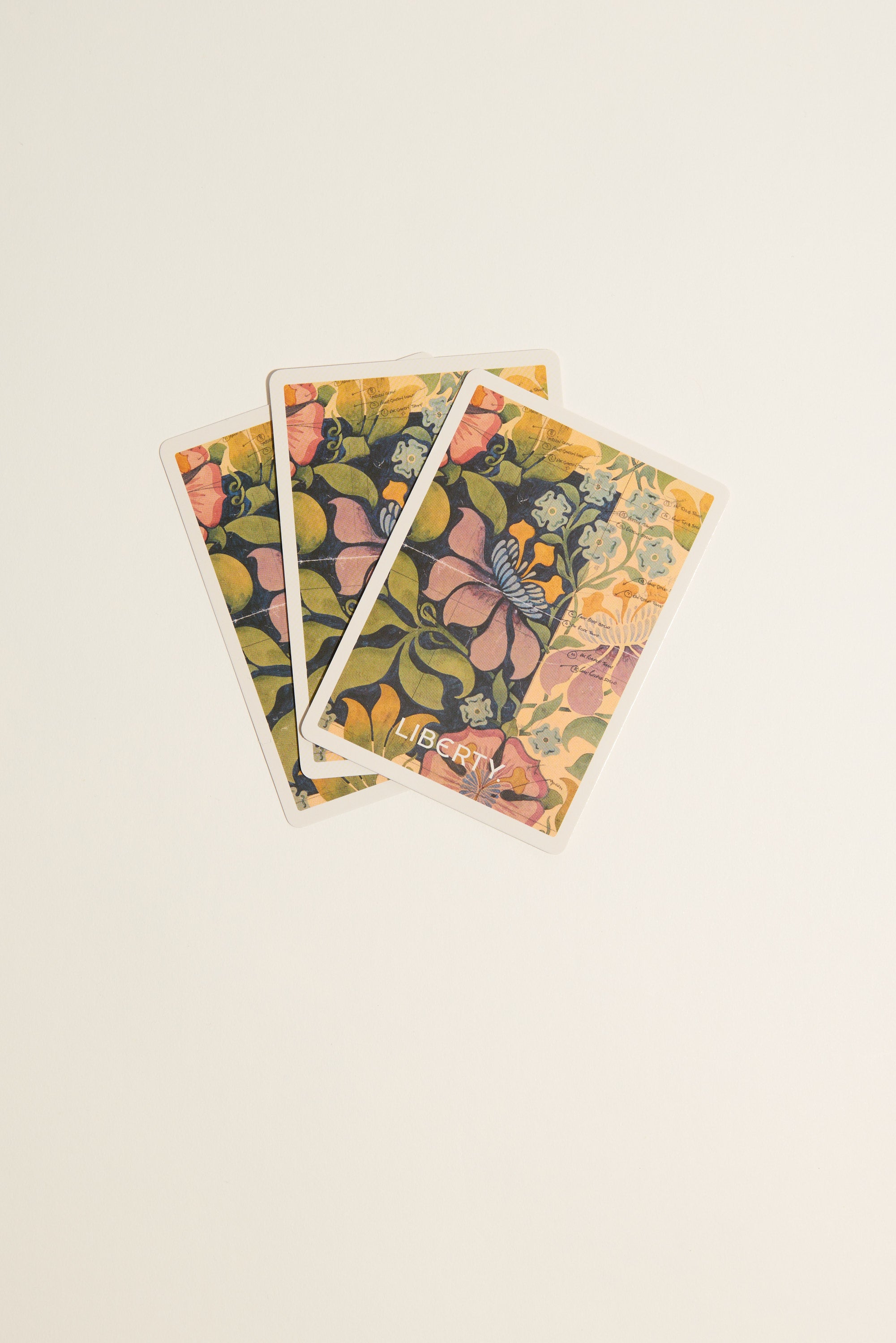 Three Liberty Archive Playing Card Decks by Other, showcasing colorful floral patterns and elegant British design, are fanned out on a plain, light background.