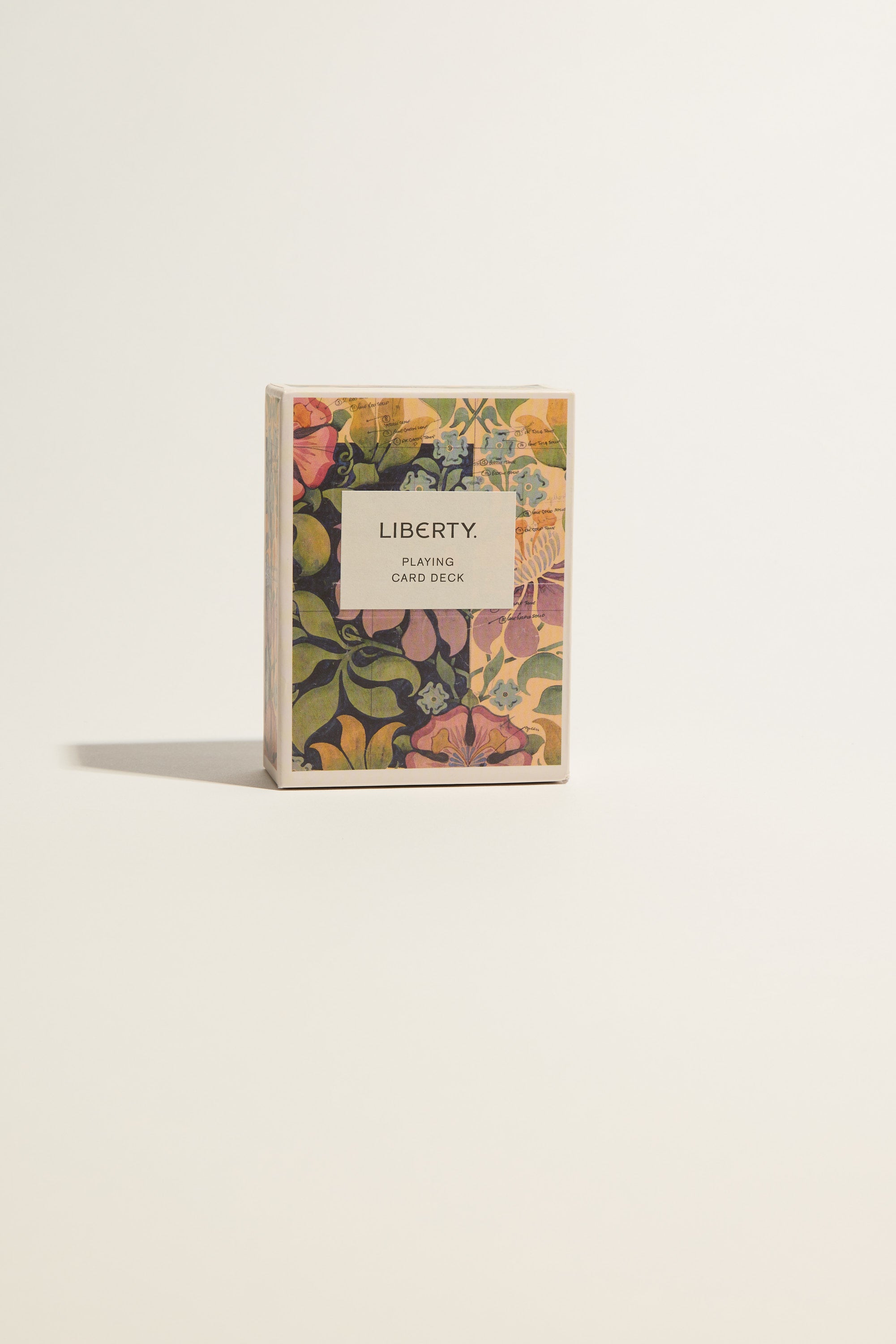 The Liberty Archive Playing Card Deck by Other, featuring a vibrant floral pattern inspired by British design, is centered on a plain light background with its shadow cast to the left.