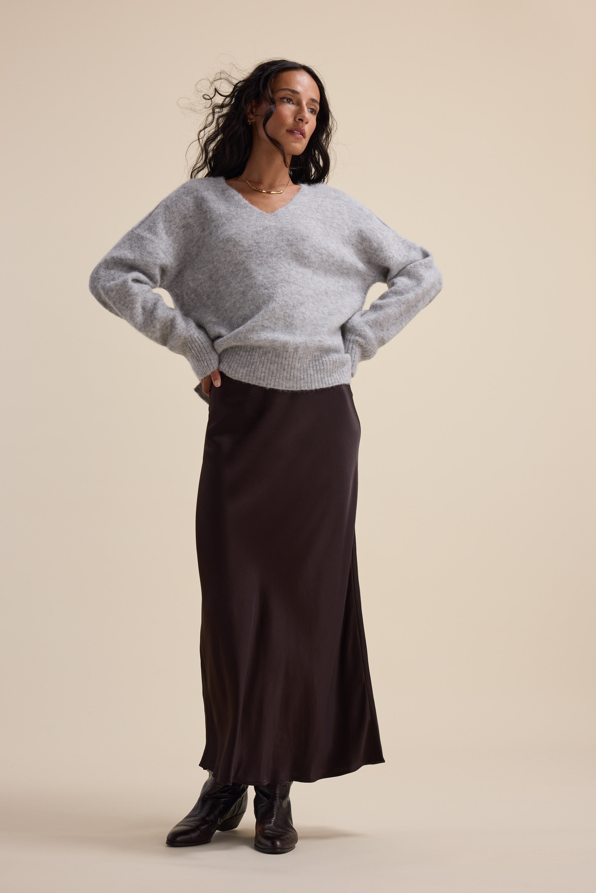 Woman in gray sweater and Max The Perfect Slip Skirt stands against a beige background.