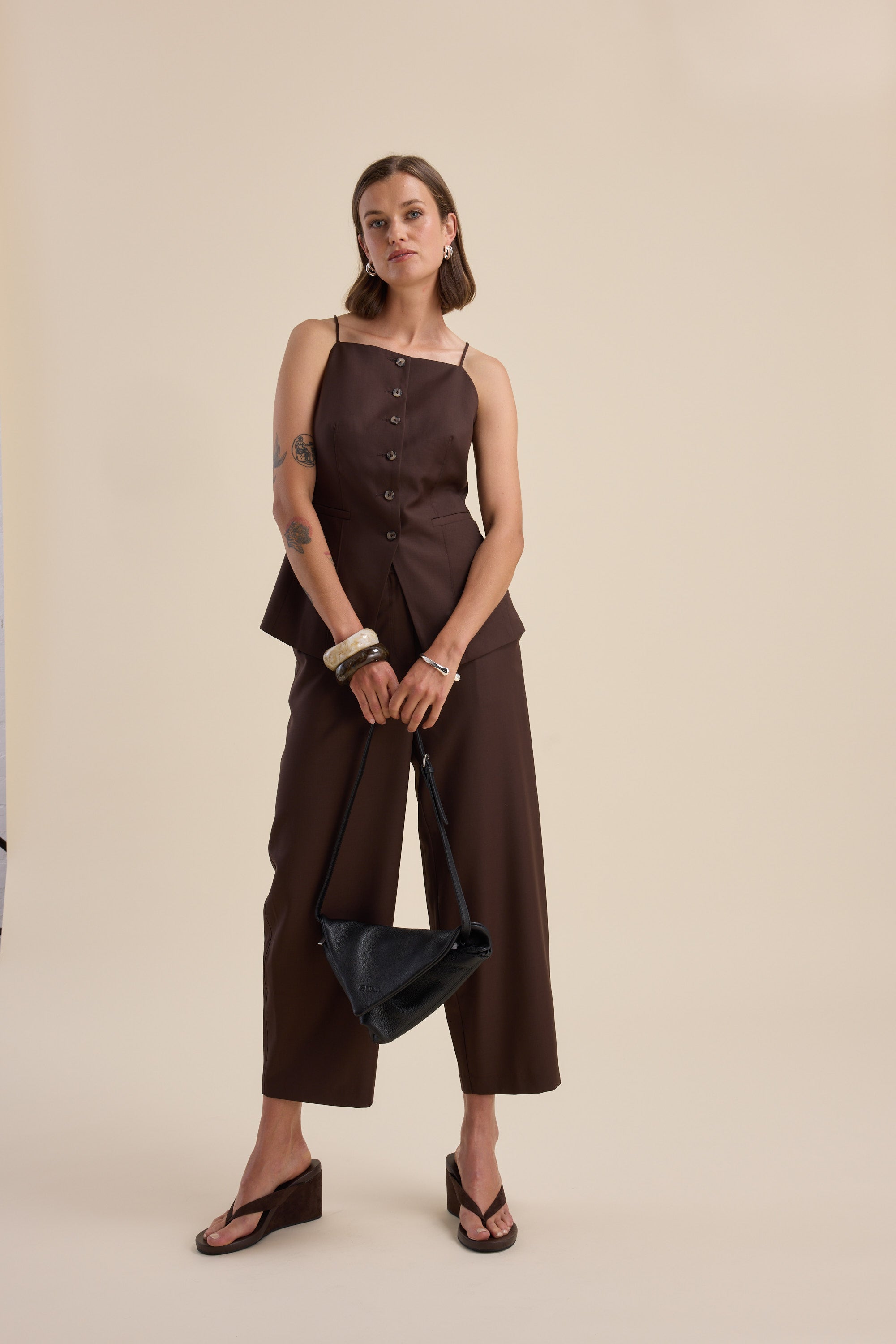 Woman in The Wool Blend Vest by Max, holding a black bag against a beige background.