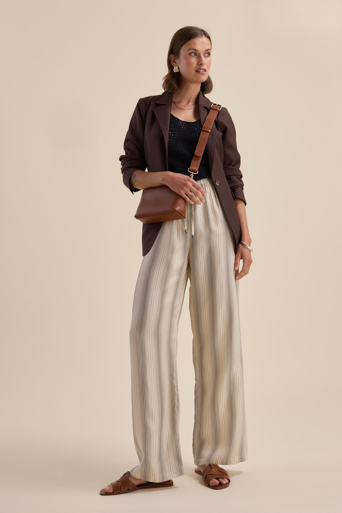 Woman in Sera Drawstring Pants by Max, dark blazer, sandals, and brown crossbody bag.