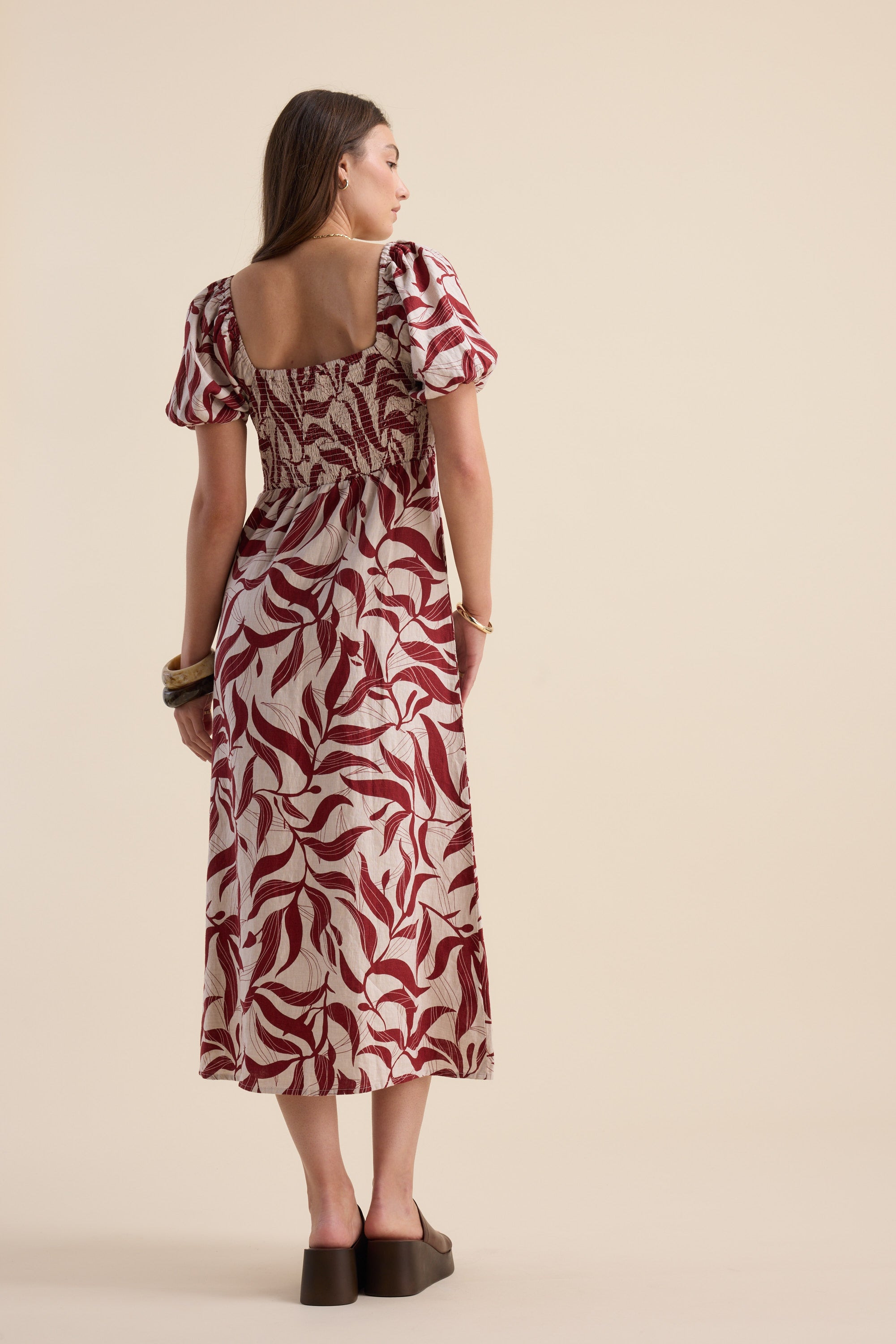 Woman in Max Camille Puff Sleeve Dress with botanical print, facing away.