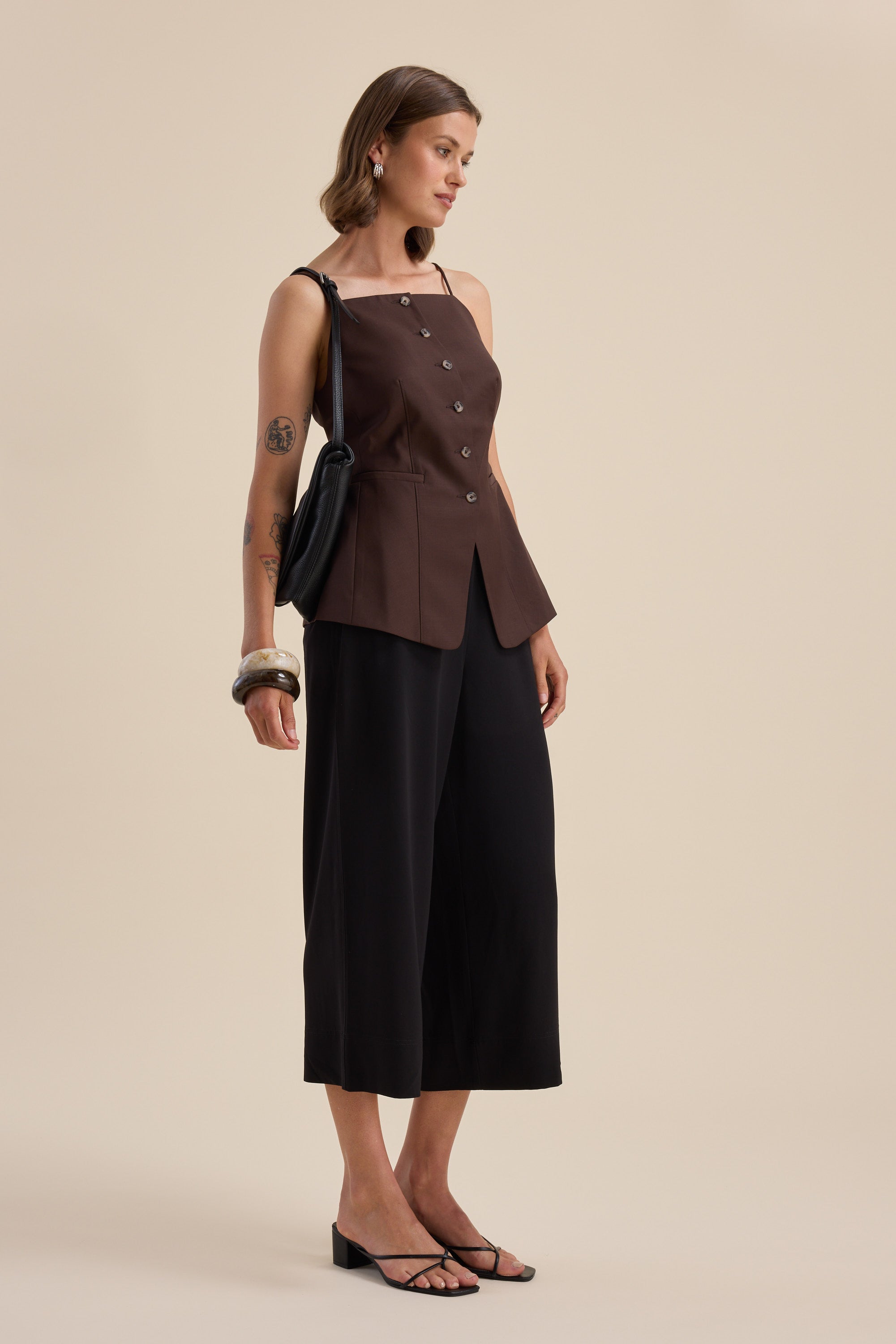 Woman in The Easy Care Wide Leg Crop Pants by Max, brown top, sandals, and a shoulder bag.