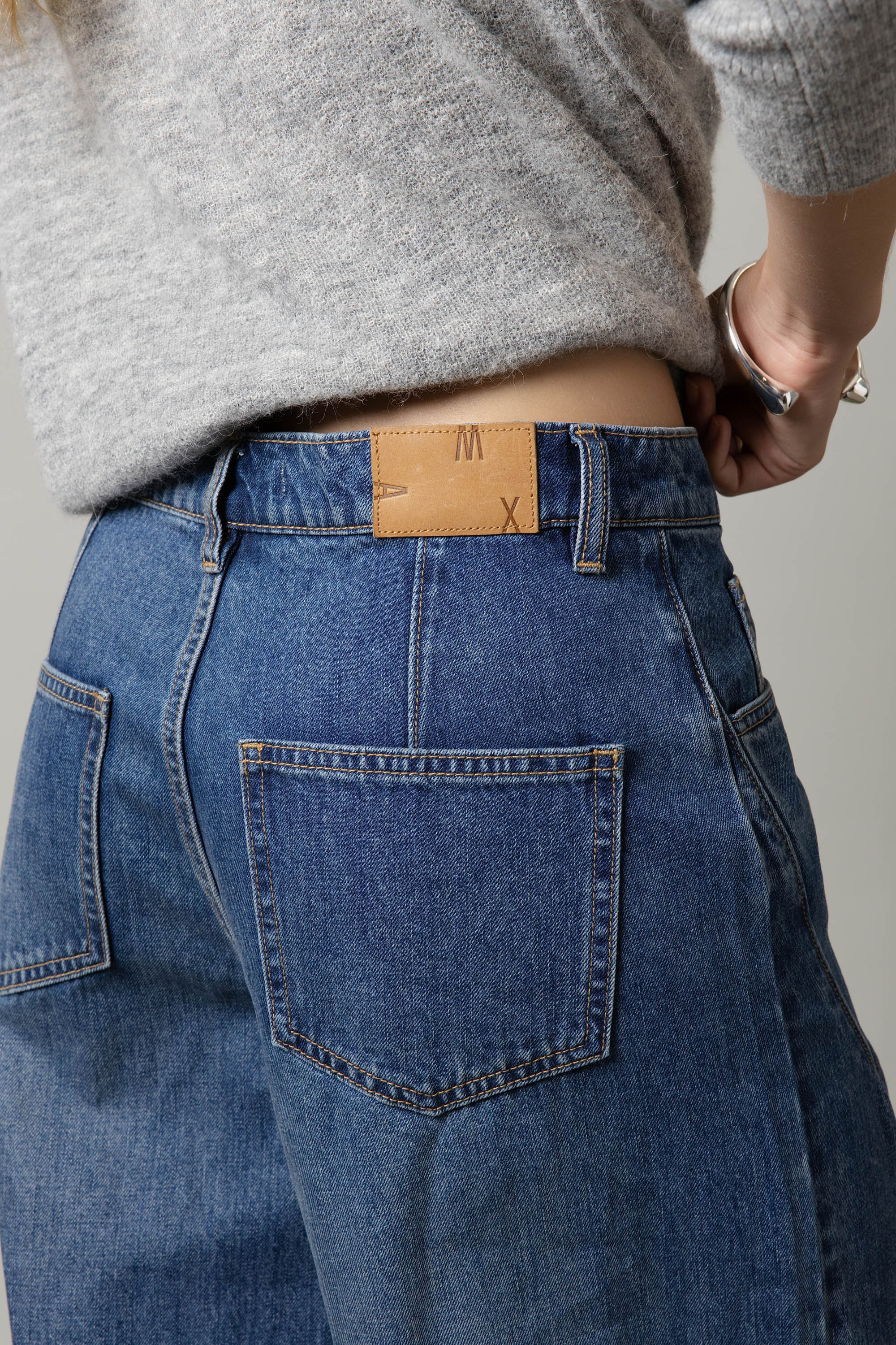 Model wears Max The Barrel Leg Jeans, highlighting the back pocket and waistband with a gray sweater.