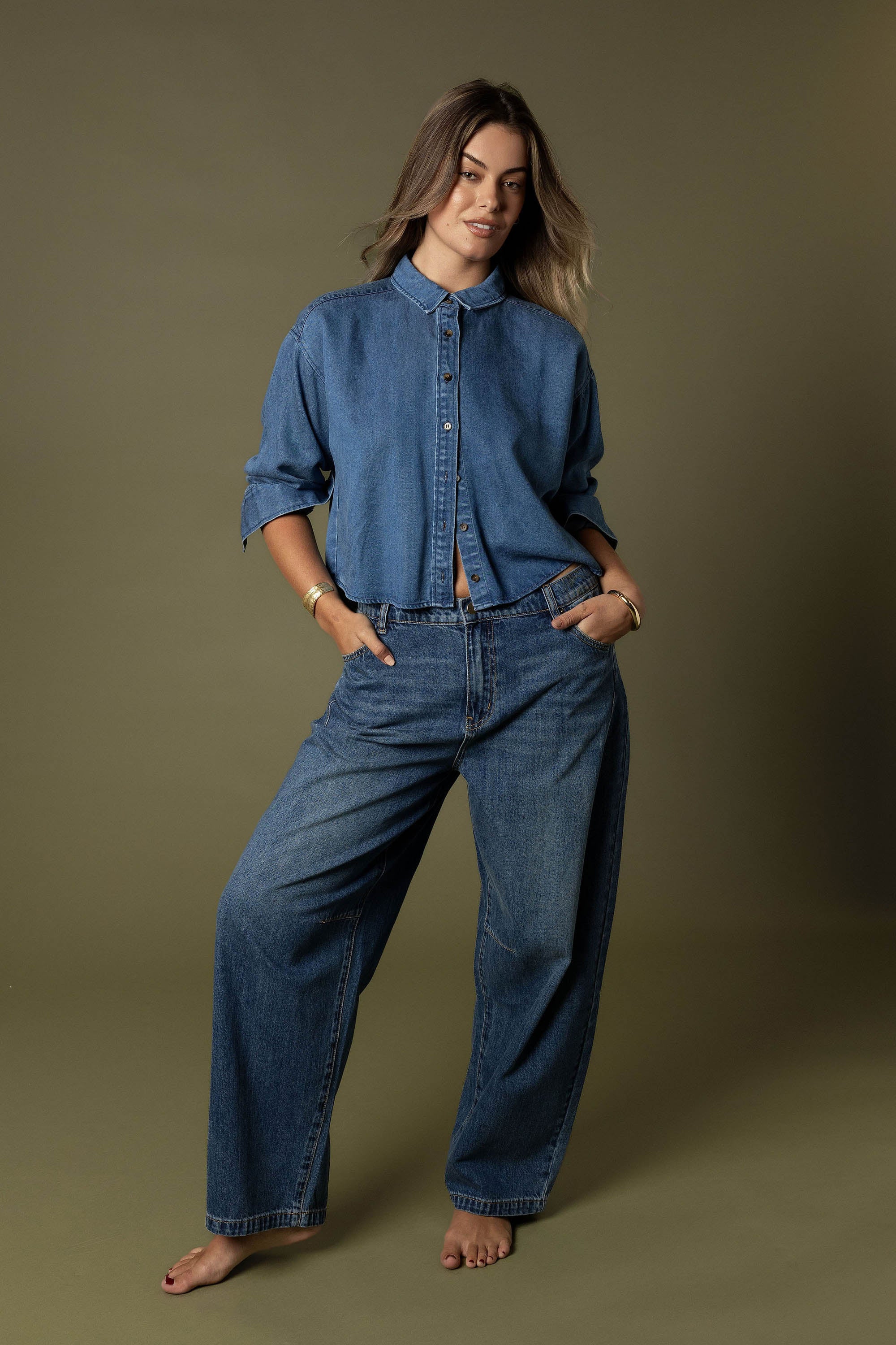 Woman wears Max's The Barrel Leg Jeans, barefoot against a plain brown background.