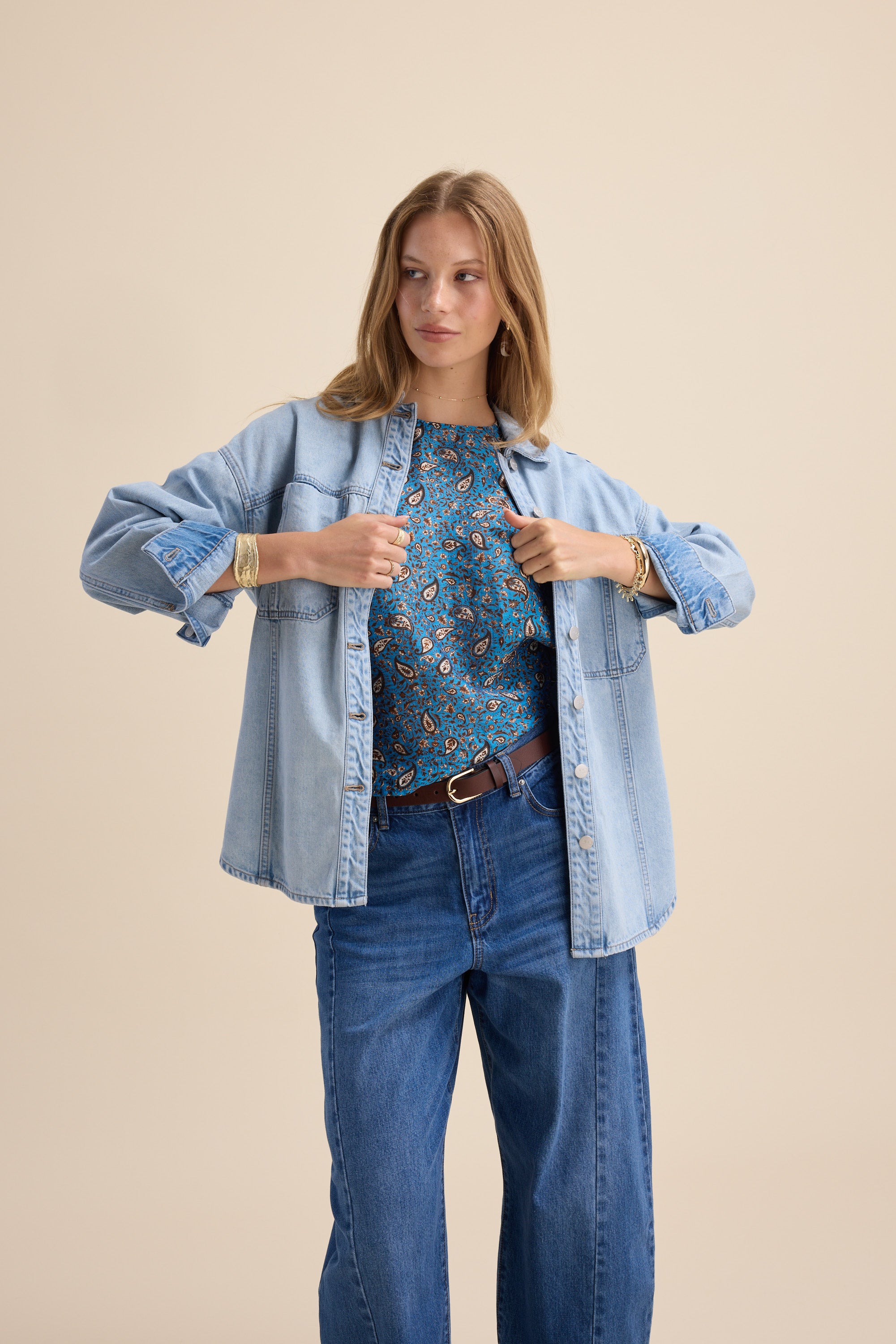 Woman in denim shirt and jeans over Max Sydney Back Detail Top, against a beige background.