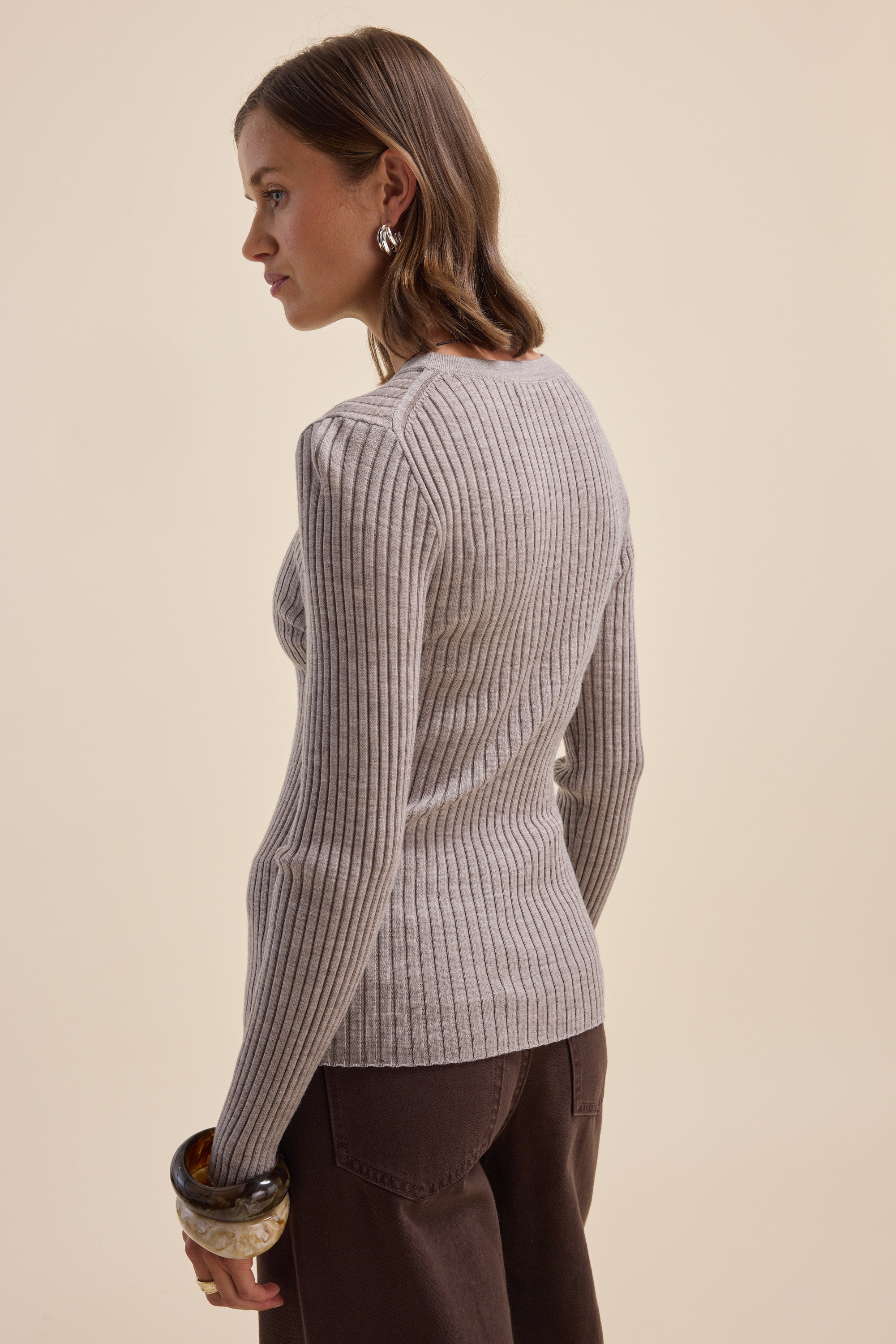 Woman in an Elementary ZQ Merino Crew Neck Top and brown pants, facing away from the camera.