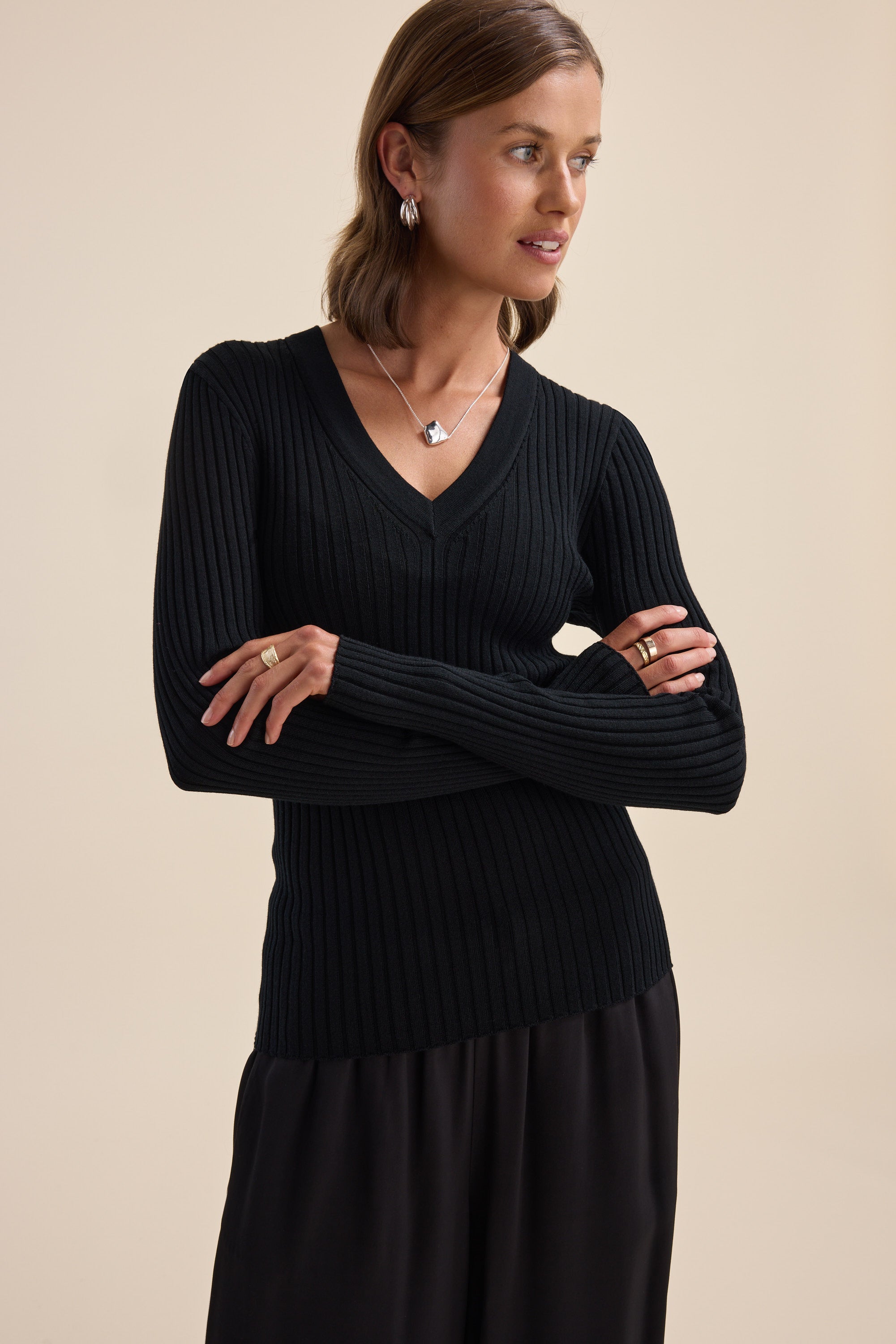 Woman wears Elementary ZQ Merino V Neck Top, arms crossed, looking to the side.