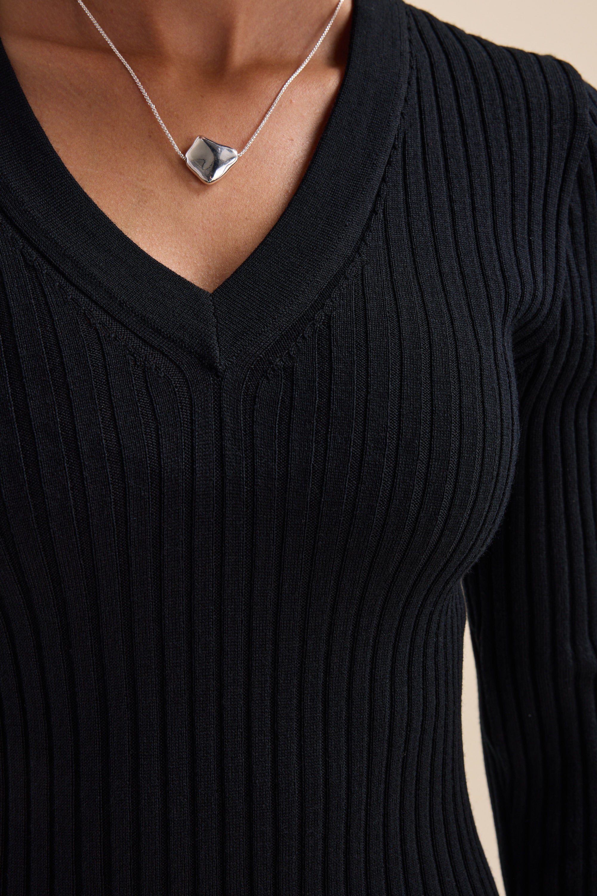 Person wearing an Elementary ZQ Merino V Neck Top and a silver geometric pendant necklace.