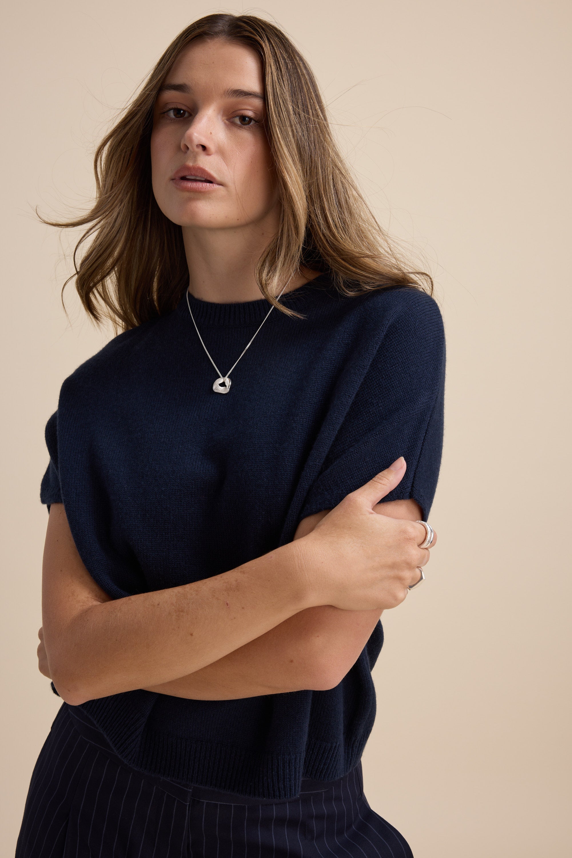 Woman in the Elementary Cashmere Blend Drop Shoulder Top by Elementary, against a beige background.
