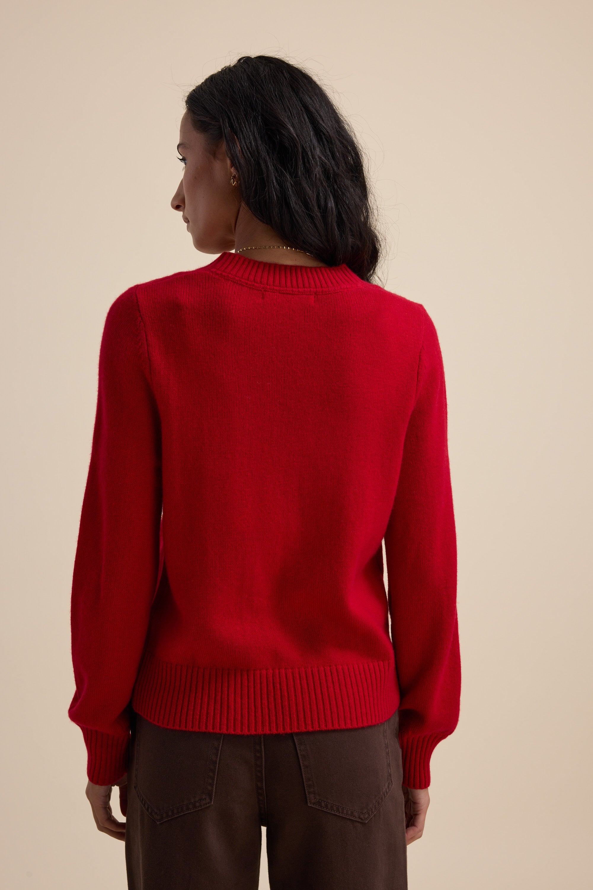 Woman in a bright red Elementary Cashmere Blend Crew Neck Sweater, brown pants, beige background.