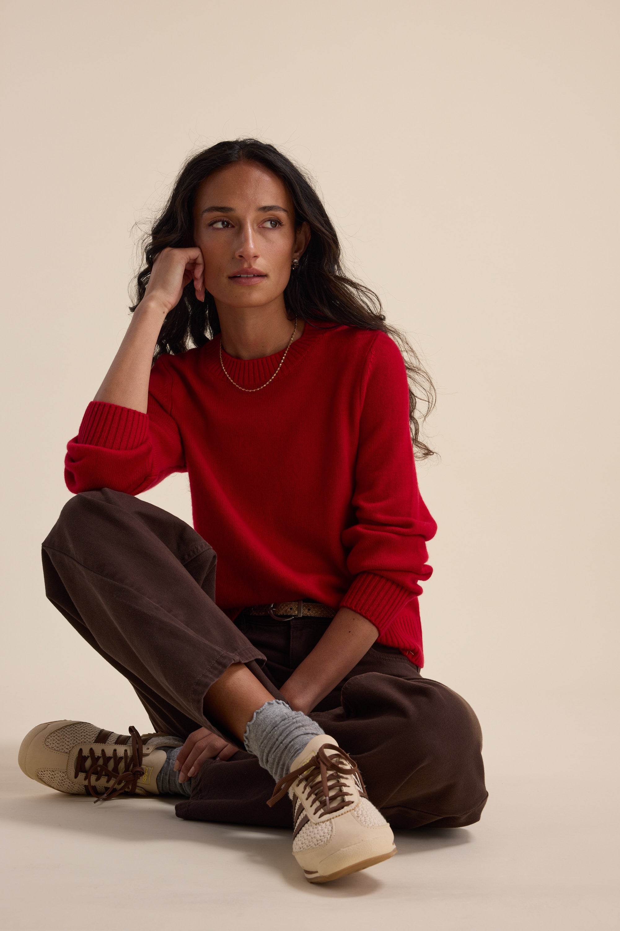 Woman in an Elementary Cashmere Blend Crew Neck Sweater sits on the floor, gazing to the side.