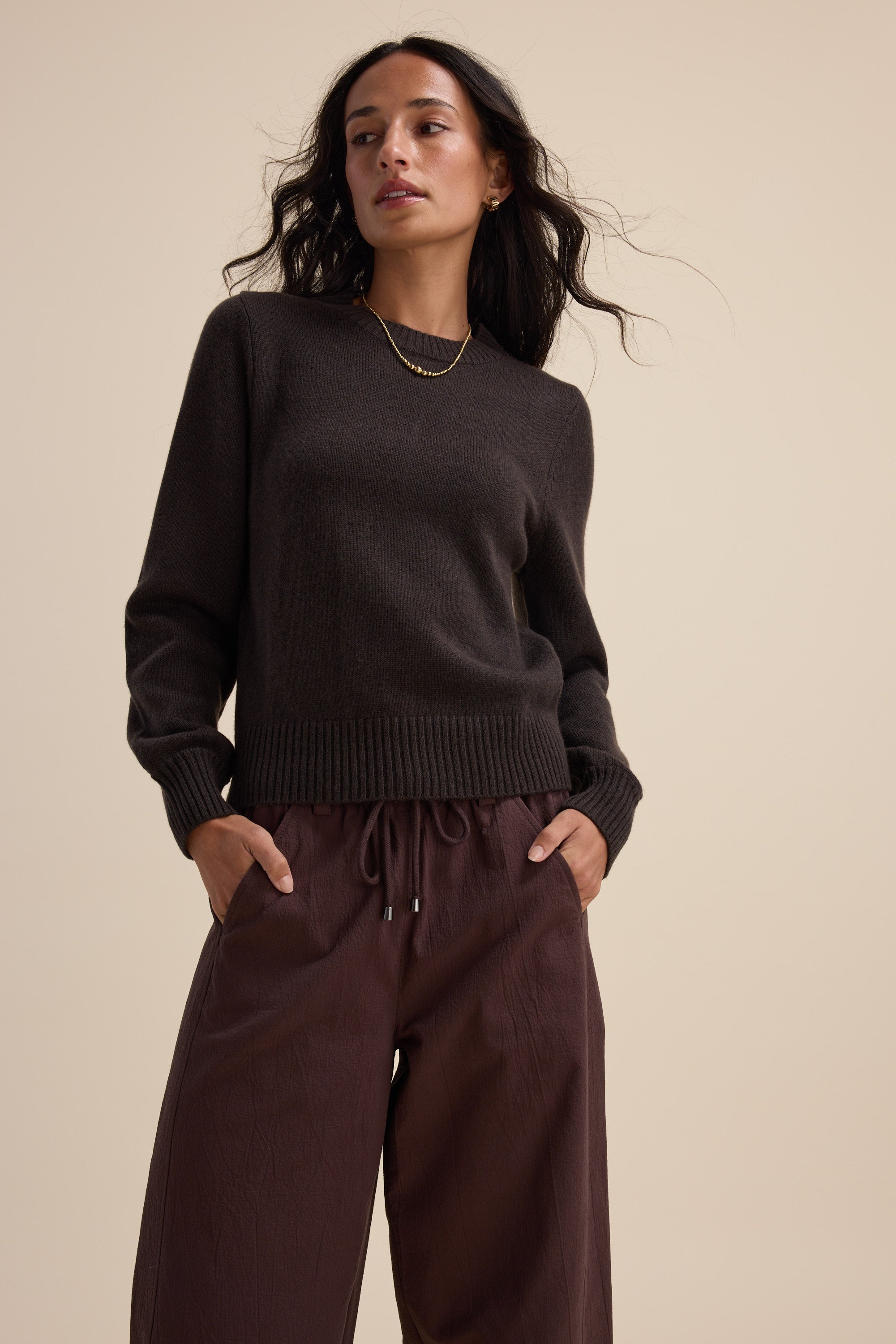 Woman in an Elementary Cashmere Blend Crew Neck Sweater stands with hands in pockets.
