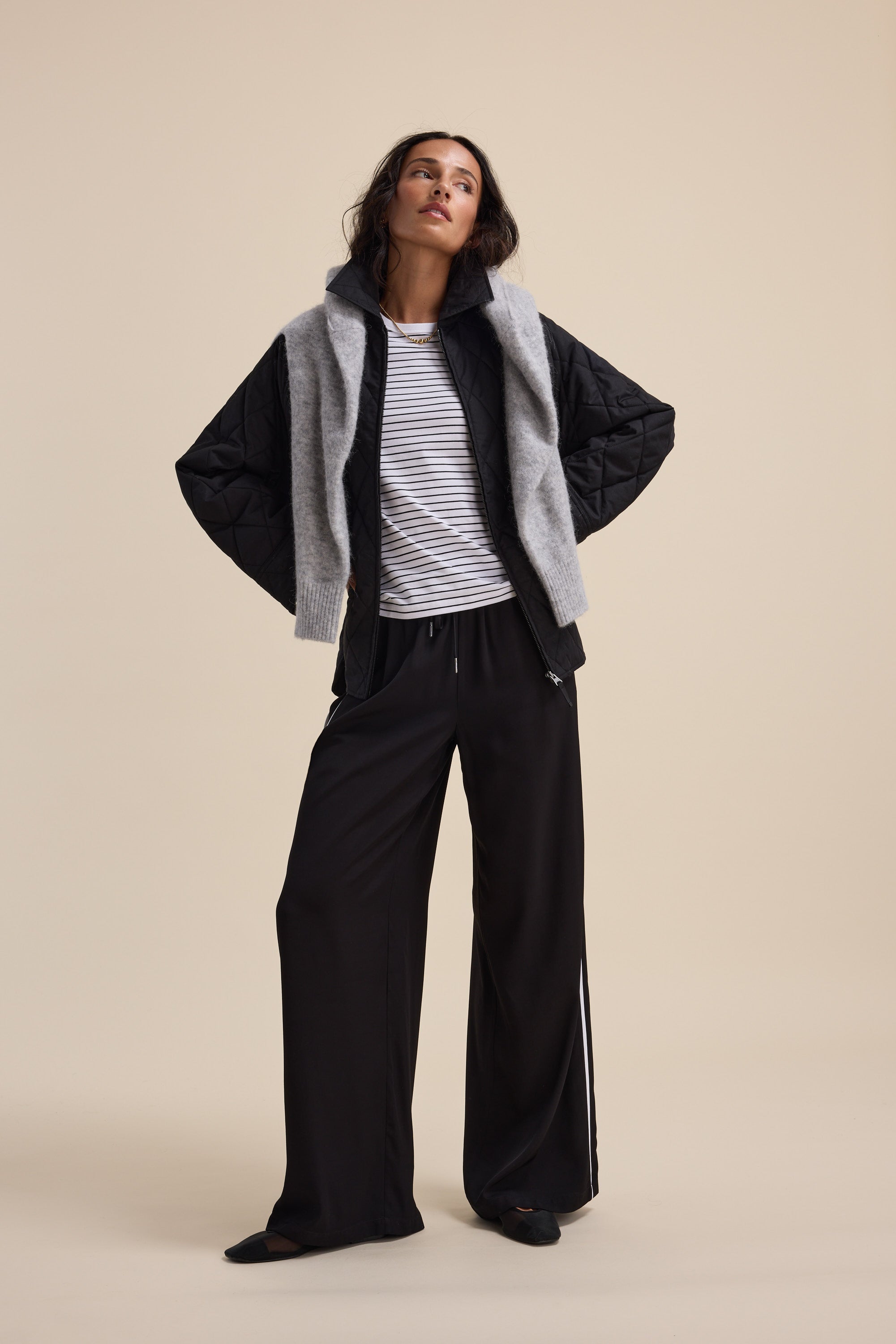 Woman in black wide-leg pants, striped shirt, and Elementary Quilted Puffer by Elementary.