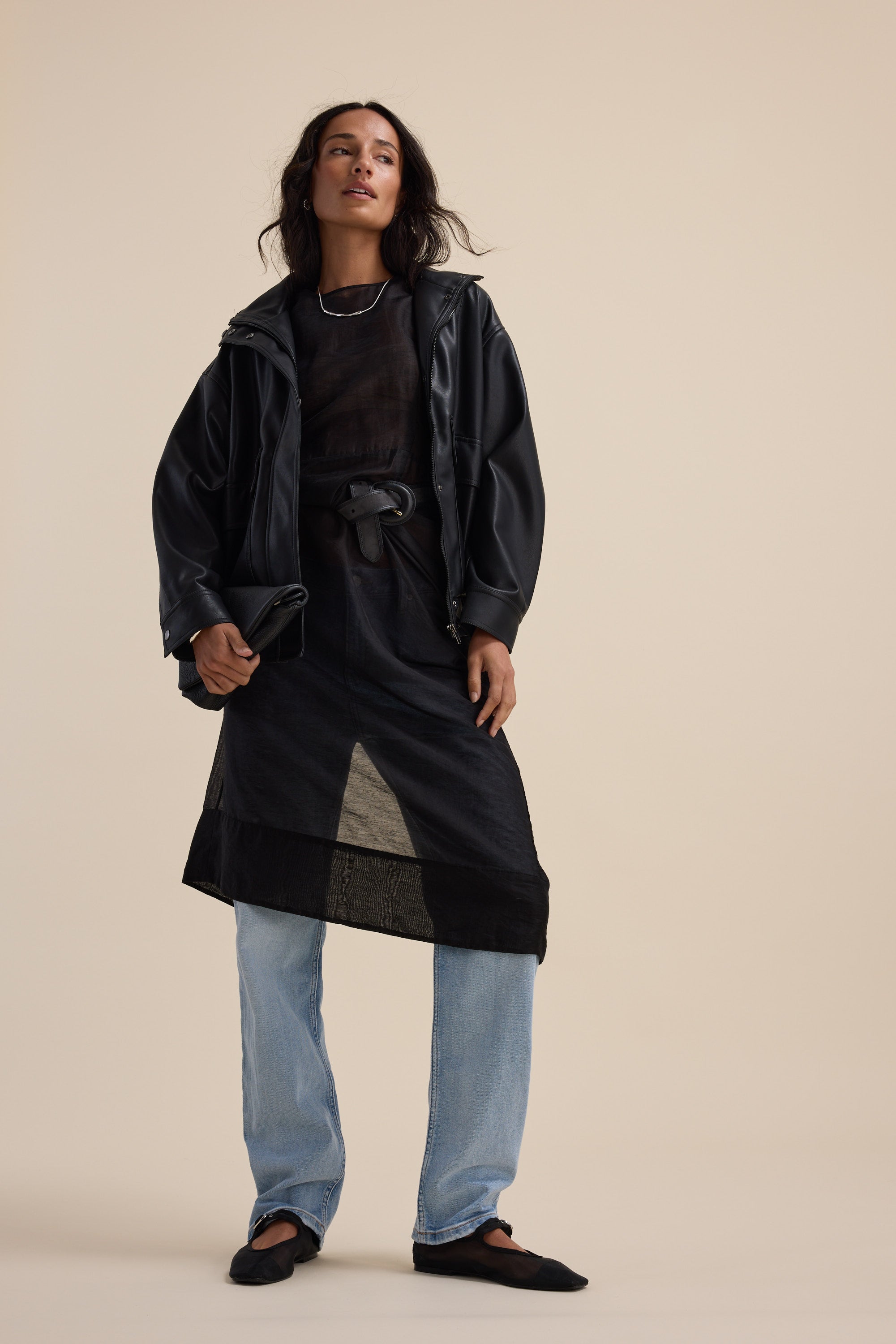Person in The Sheer Layering Dress by Max, light blue jeans, black jacket, beige background.