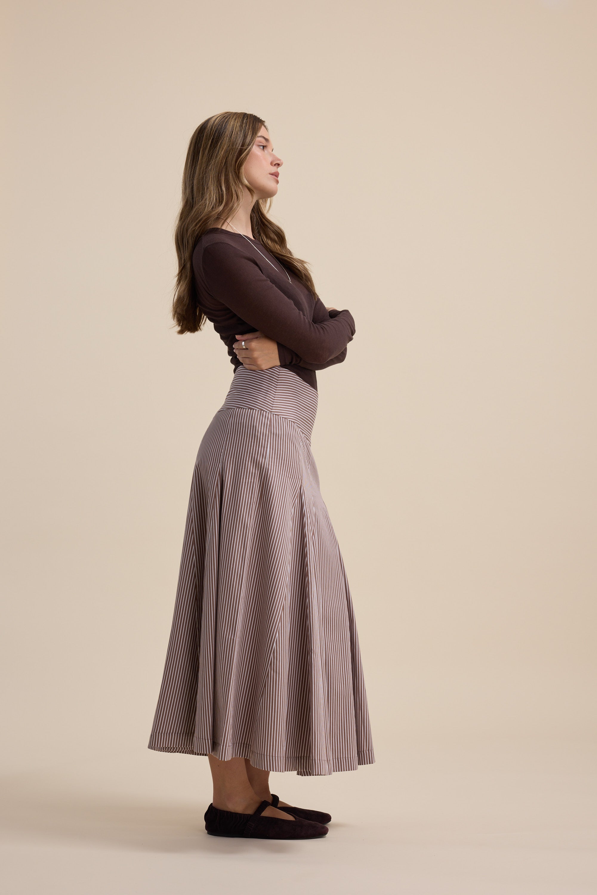 Woman in Max’s Marley Panel Seam Skirt stands sideways with arms crossed.